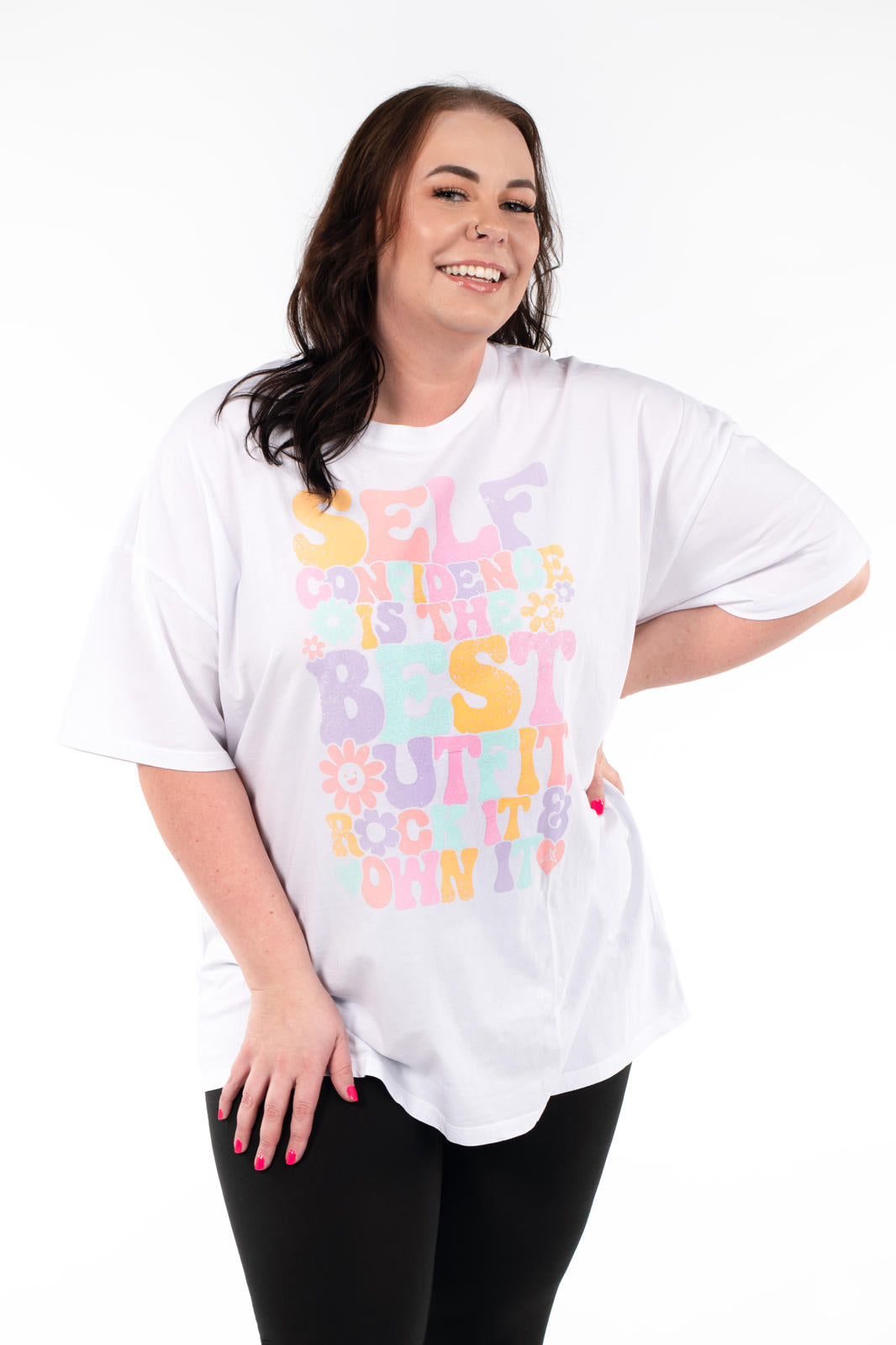 Smiling woman wearing SweetTops Vintage Graphic Tee with colorful positive affirmation text on white oversized shirt