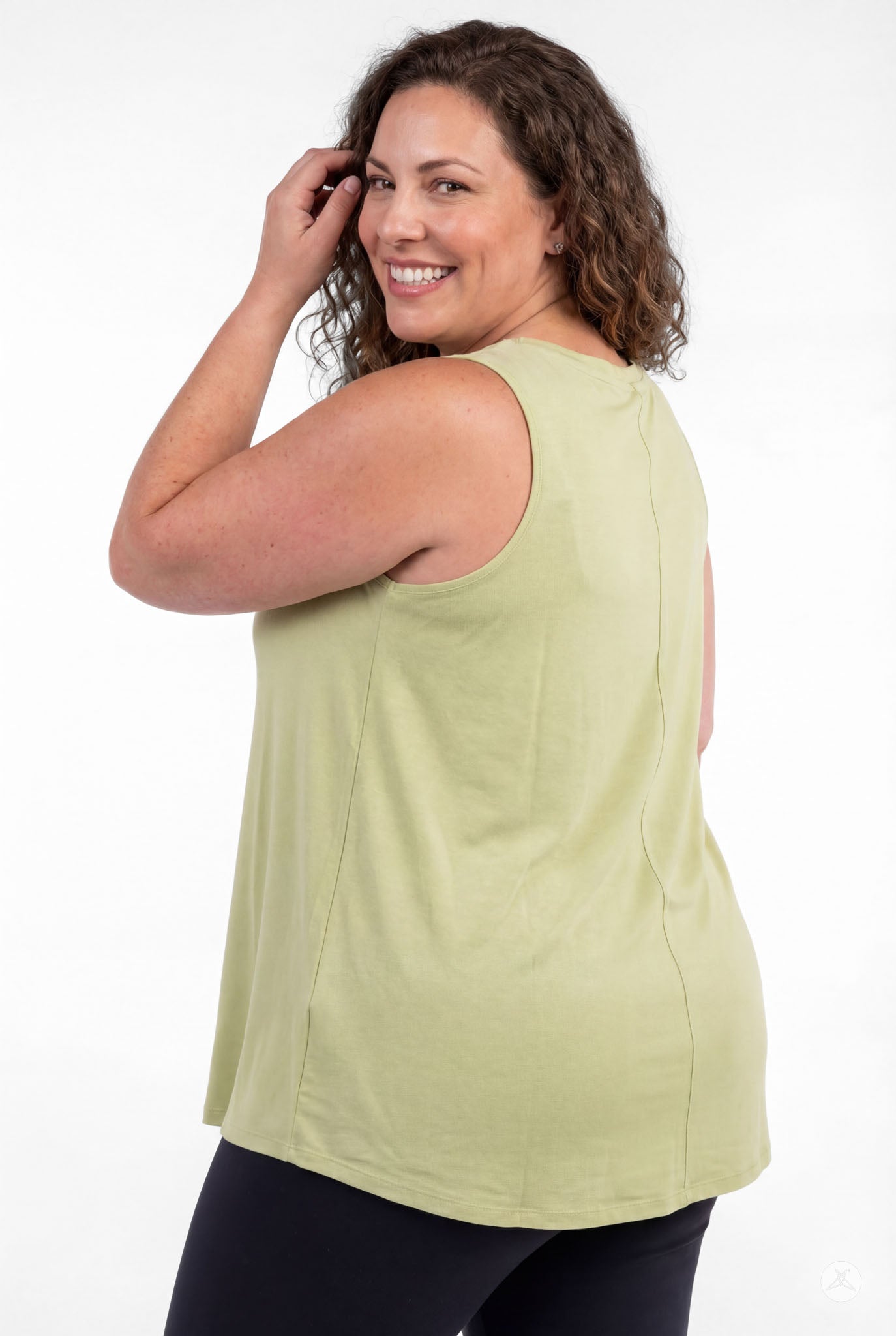Plus size woman smiling wearing light green High Neck Tank by sweettops standing relaxed against white background