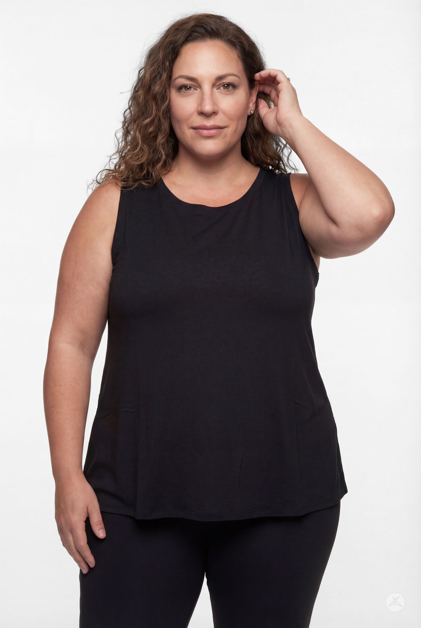 Plus size woman wearing black sleeveless High Neck Tank by sweettops standing casually with hand near hair against white backdrop