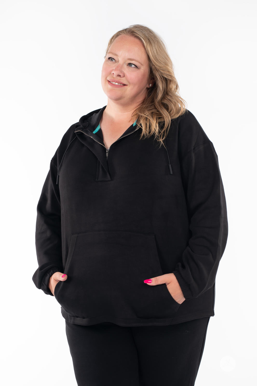 Plus-size woman wearing black SweetTops All Day Hoodie with kangaroo pocket and relaxed fit on white background