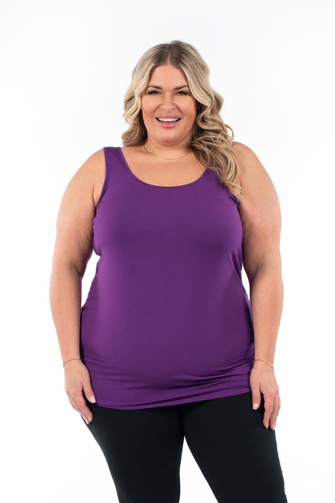 Plus size woman smiling wearing deep purple Classic Layering Tank by SweetLegs Canada paired with black leggings on white background