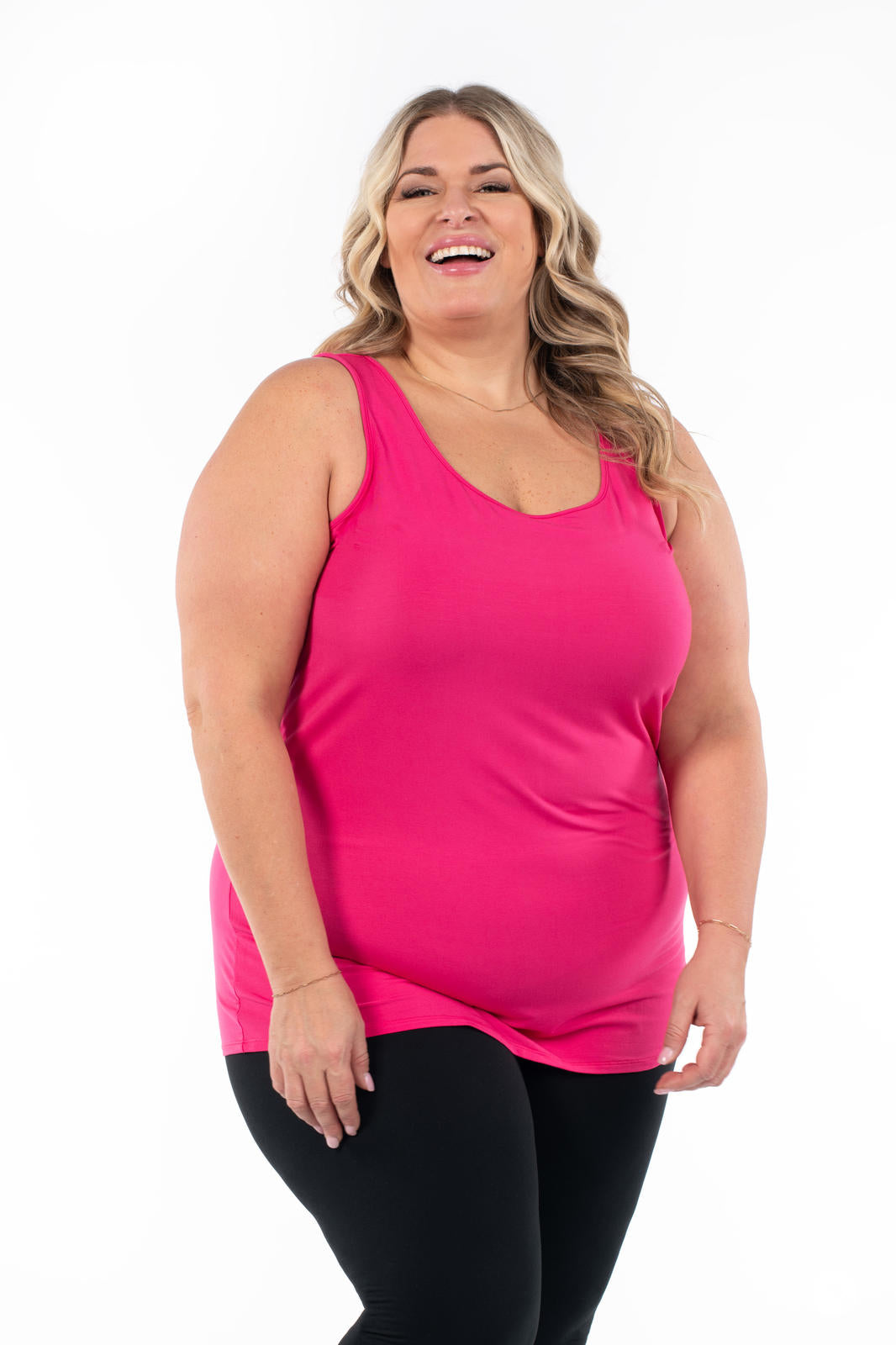 Smiling plus size woman wearing bright pink Classic Layering Tank by SweetLegs Canada with black leggings on white background