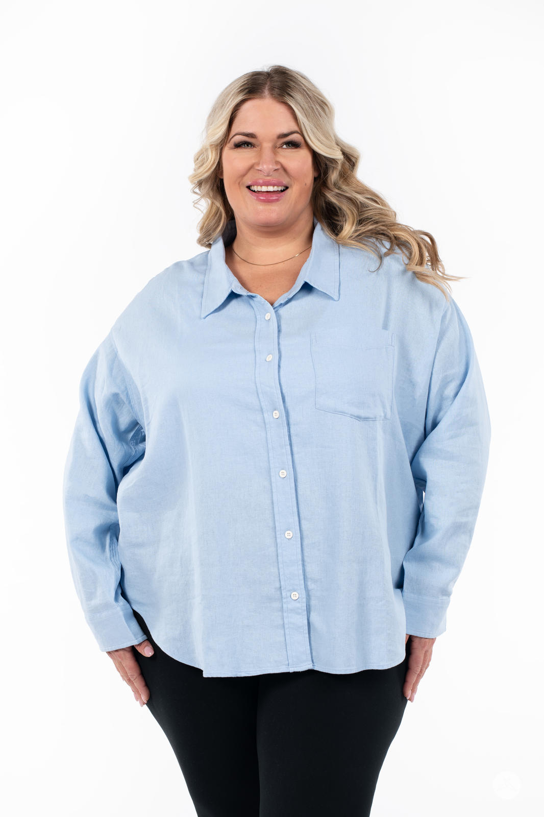 Plus-size model wearing SweetTops Classic Linen Shirt in light blue with chest pocket and relaxed fit smiling on white background