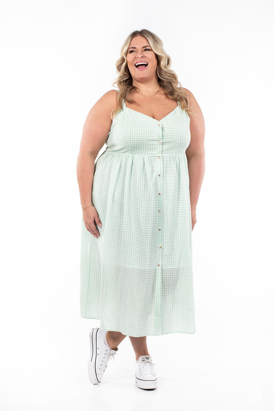 Plus-size model smiling and wearing SweetTops Gingham Dress in light green with button front and A-line silhouette