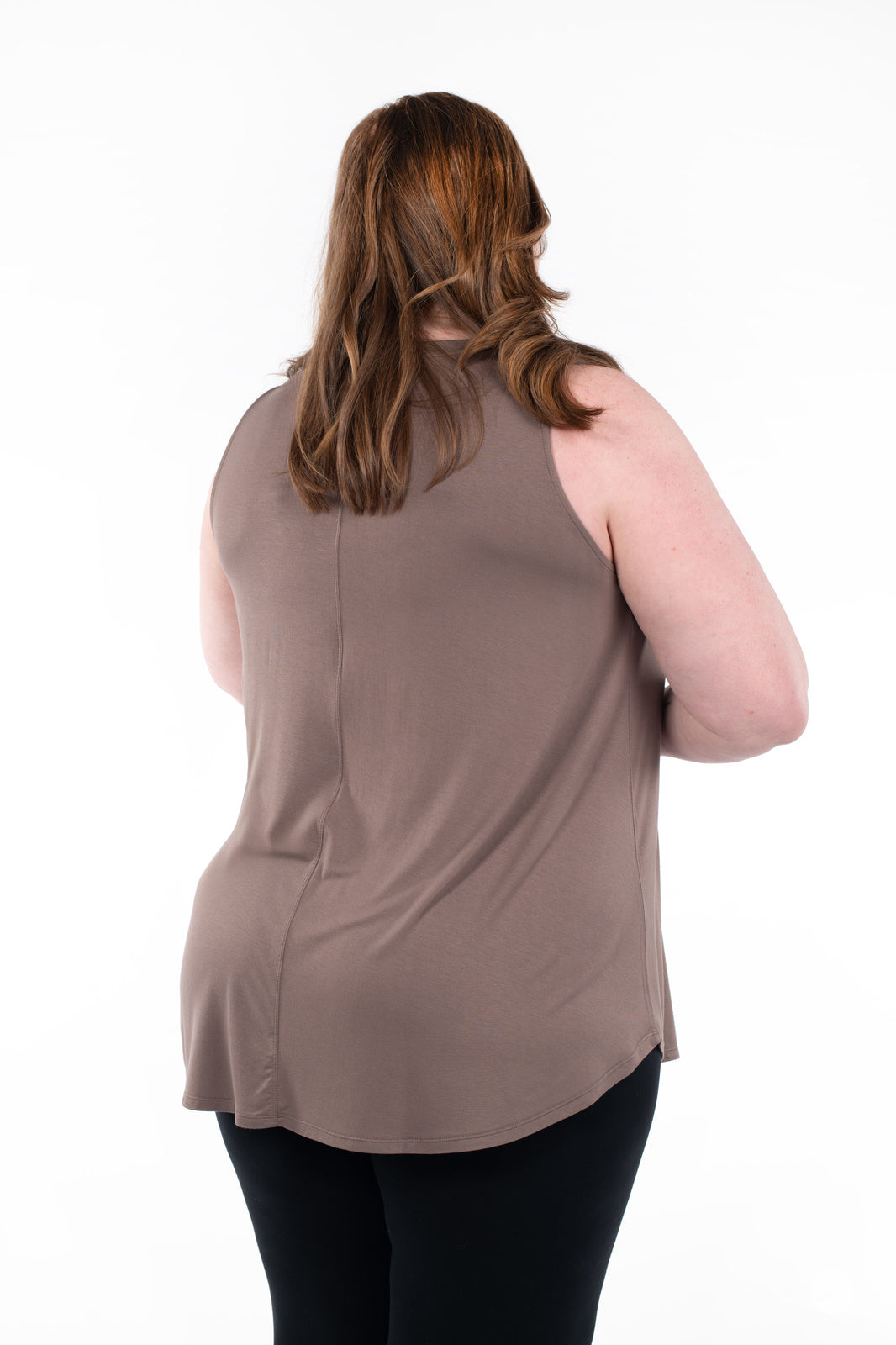 Plus-size model shown from back wearing SweetTops High Neck Swing Tank in Latte with black pants on white background
