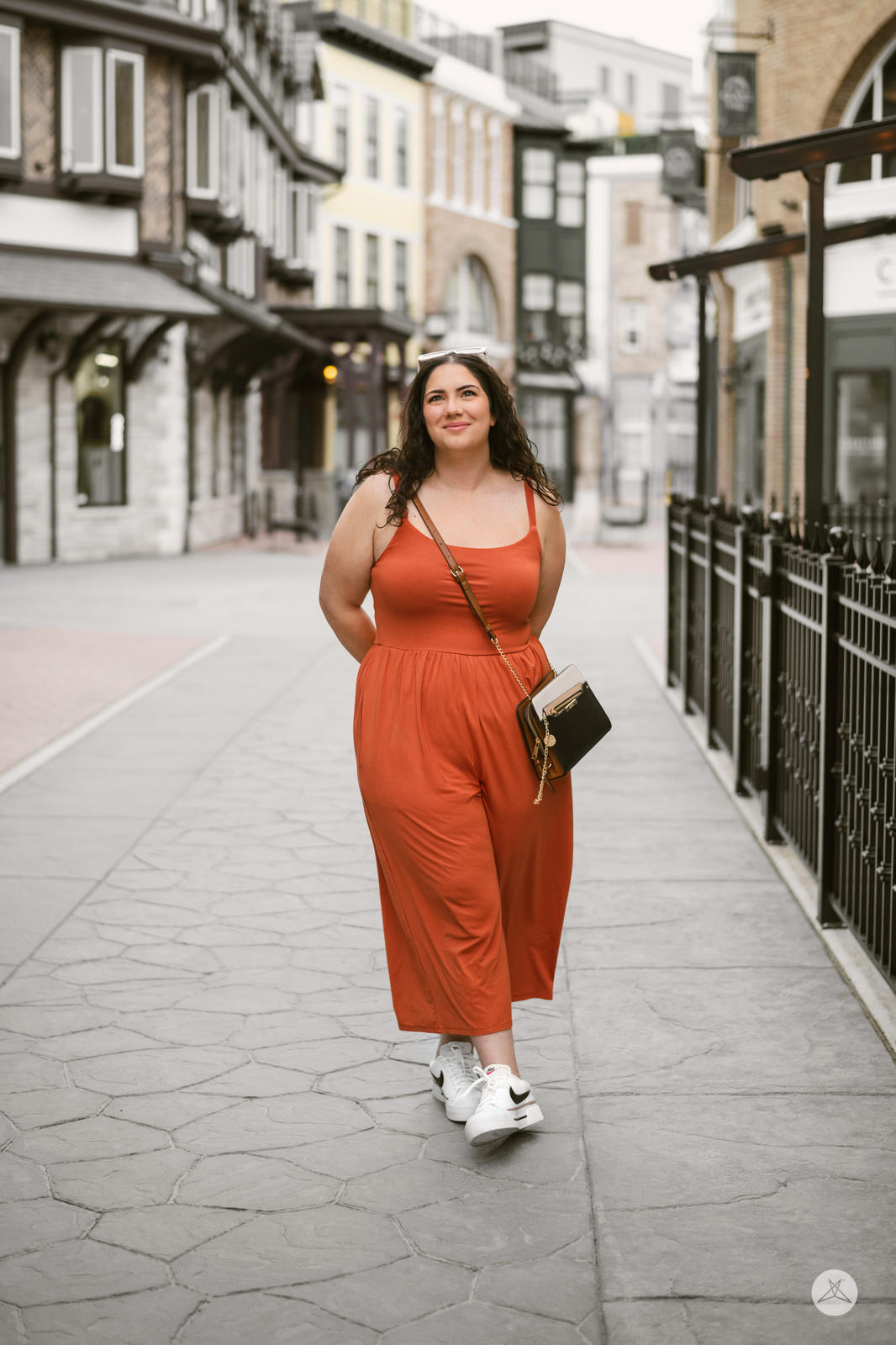 Plus-size model walking outdoors wearing SweetLegs Cropped Wide Leg Jumpsuit in rust with relaxed fit and sleeveless design