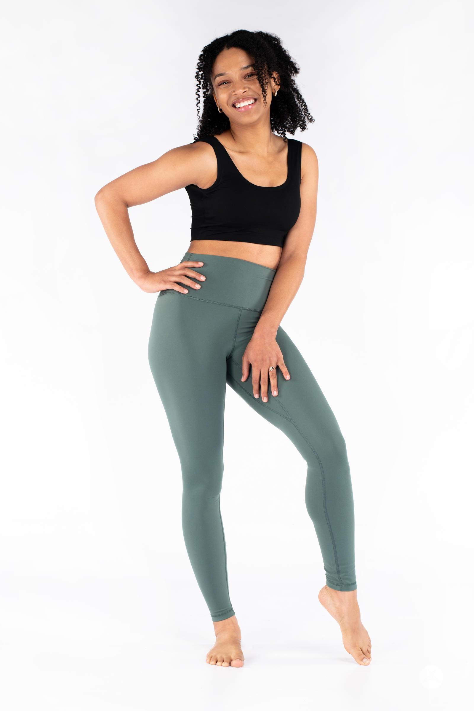 Smiling model wearing sage green Free Motion Leggings by SweetLegs Athleisure standing barefoot with hand on hip