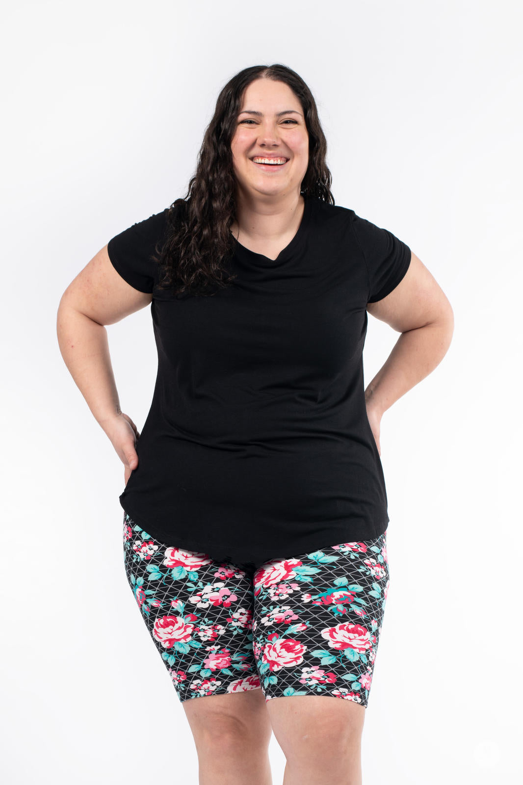 Smiling woman wearing SweetLegs Gracie Rose Refreshed Biker Shorts with floral and lattice pattern and black top