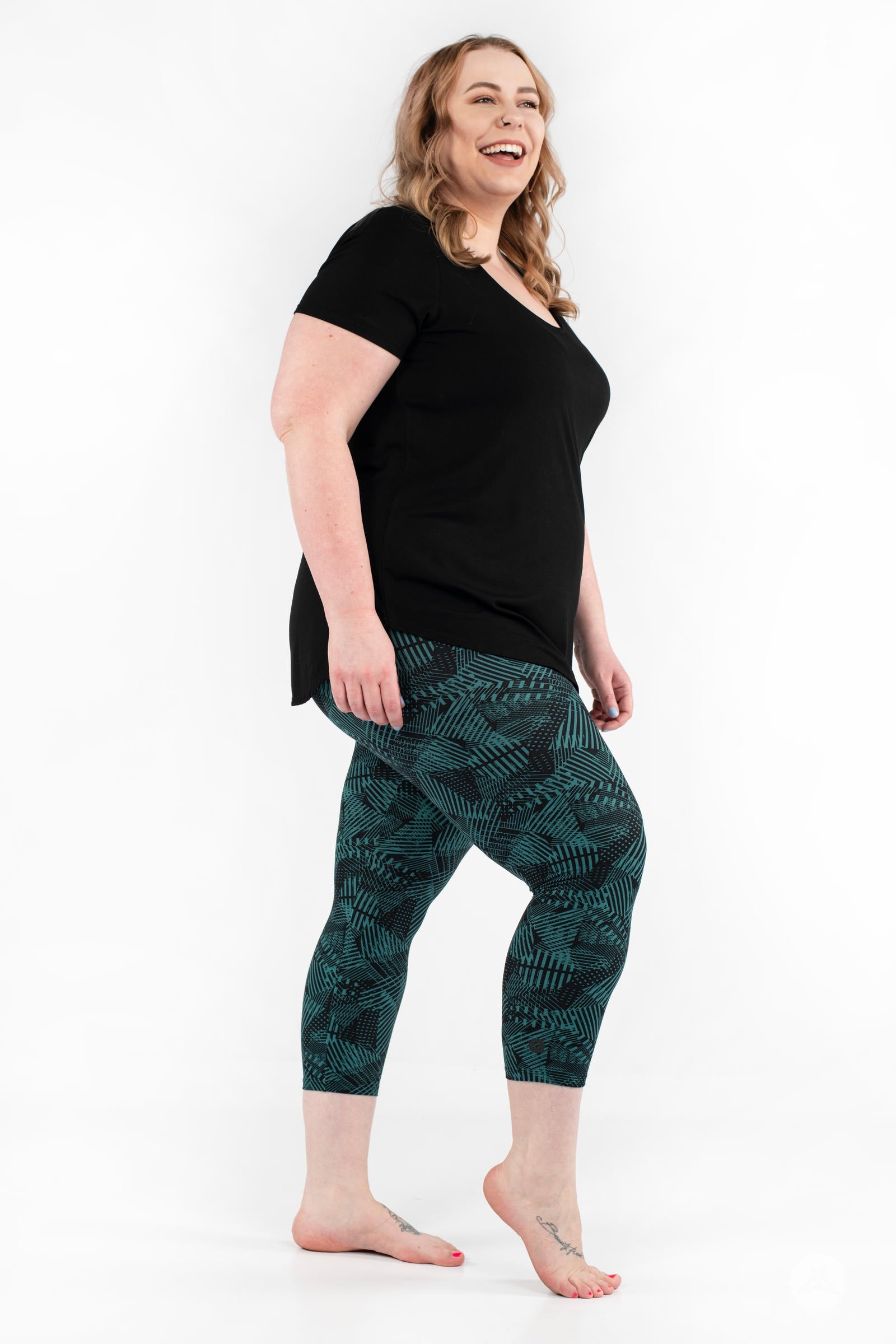 Side view of plus size model wearing SweetLegs Geometric Glam Crops with teal and black geometric cropped leggings