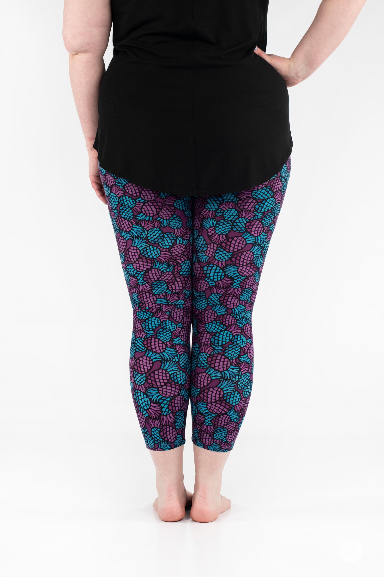 Rear view of SweetLegs Razzle Dazzle Crops with vibrant purple and teal pineapple pattern on cropped leggings