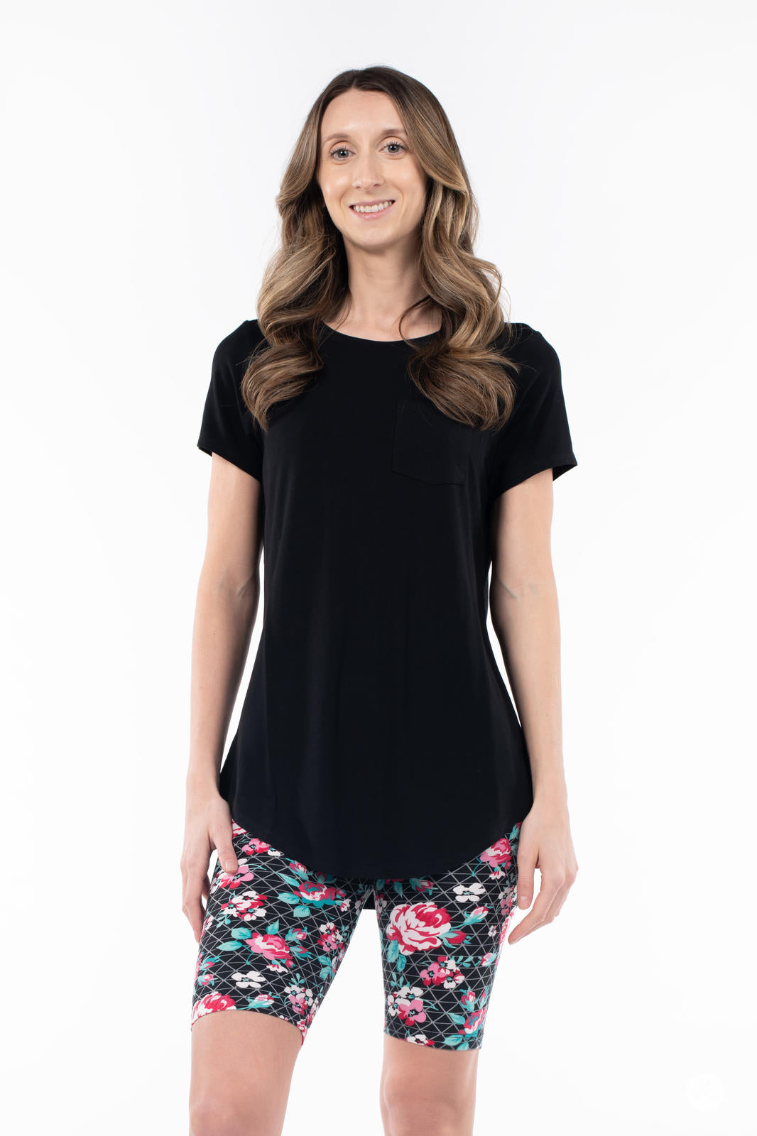 Woman wearing SweetLegs Gracie Rose Refreshed Biker Shorts with floral pattern and black short sleeve top smiling