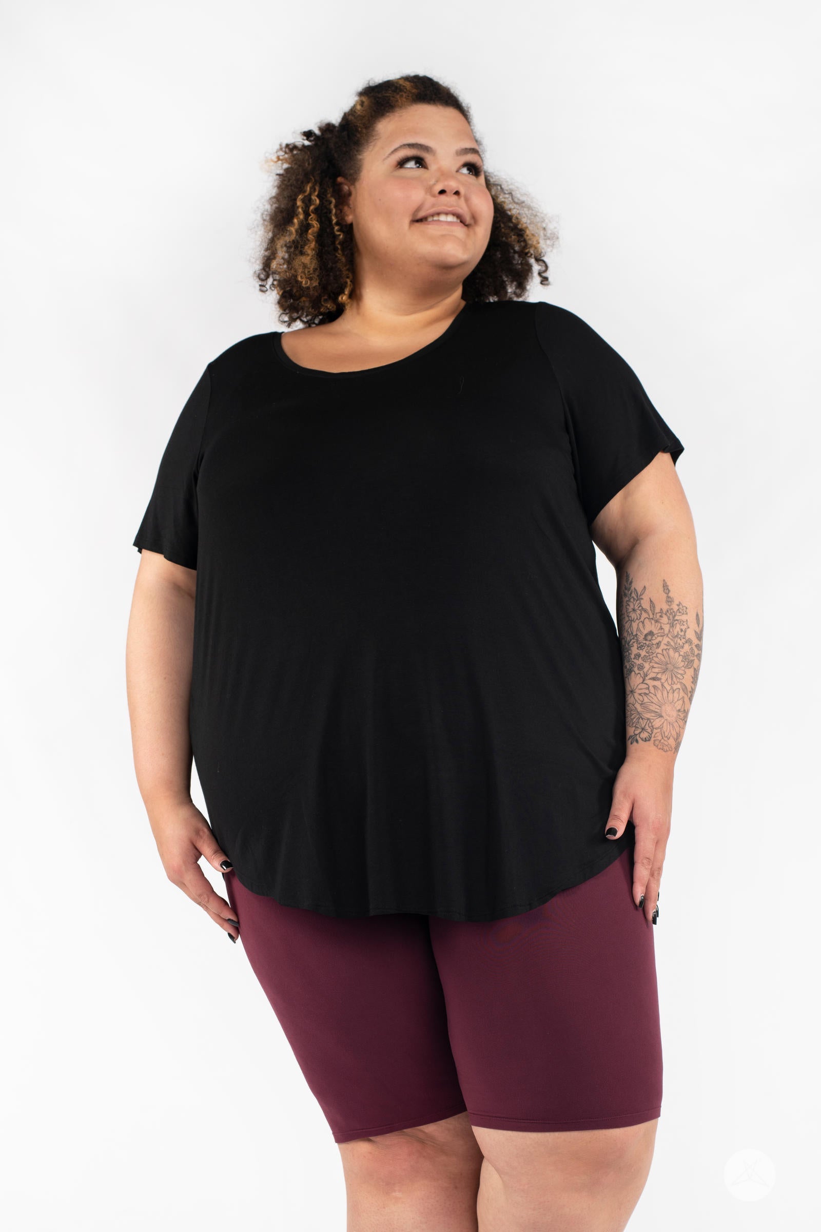 Plus-size model wearing SweetLegs Mulberry Biker Shorts in deep maroon with a loose black top on white background