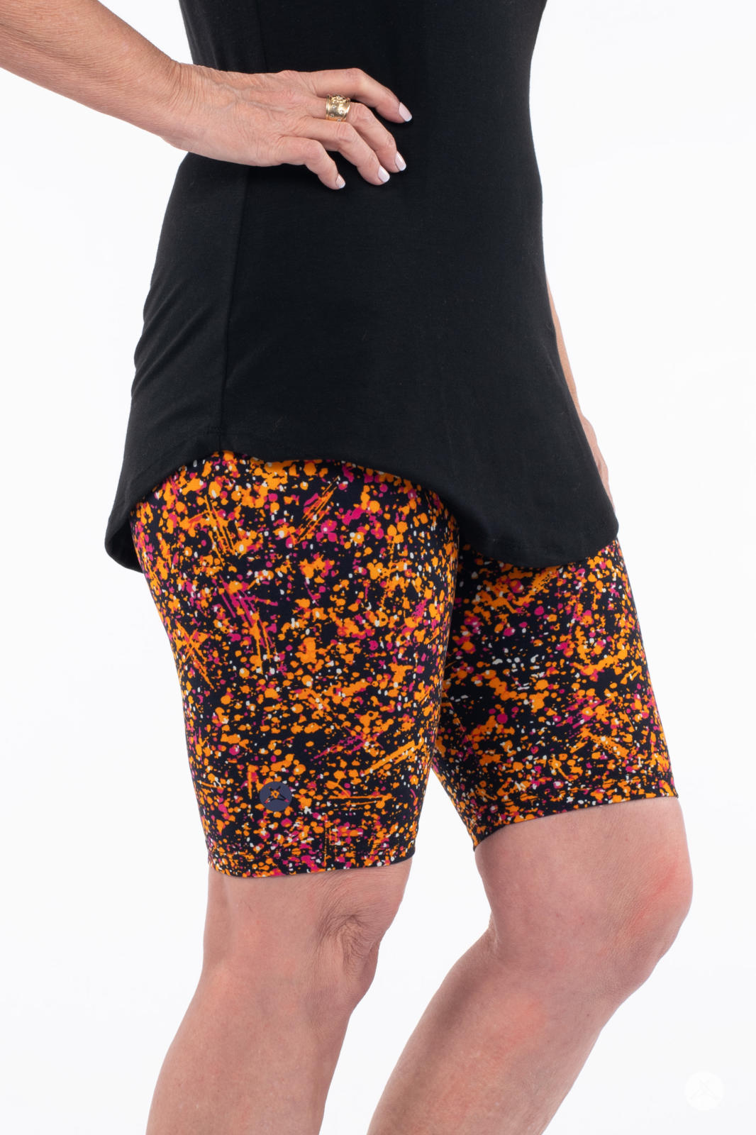 Side view of person wearing SweetLegs Splatterday Night Biker Shorts with vibrant orange and pink splatter pattern and black top