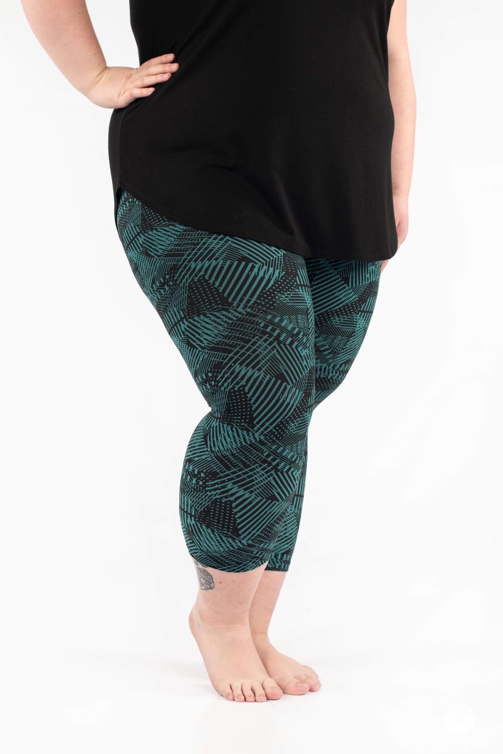 Side angle of plus size model wearing SweetLegs Geometric Glam Crops with green and black abstract pattern