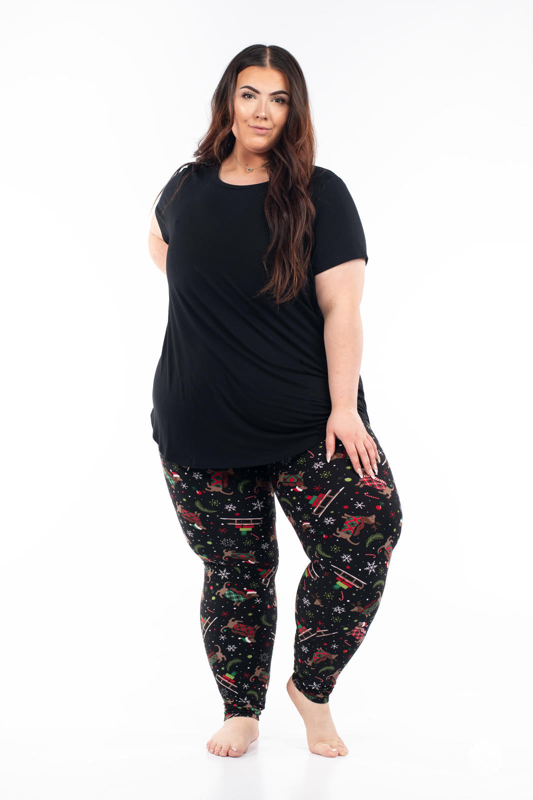 Plus-size model wearing SweetLegs Happy Pawlidays leggings with Christmas Dachshunds and festive holiday motifs on black background
