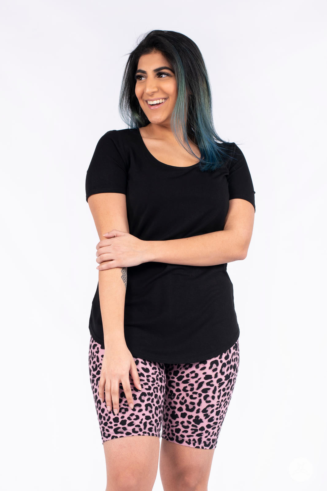 Smiling woman wearing SweetLegs A Little Wild Biker Shorts in pink leopard print with black short-sleeve top