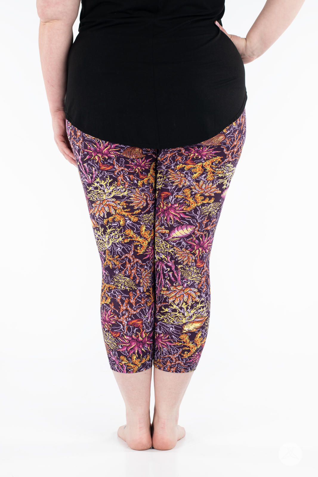 Rear view of plus size model wearing SweetLegs Coral Cove Crops with colorful sea life print cropped above ankle