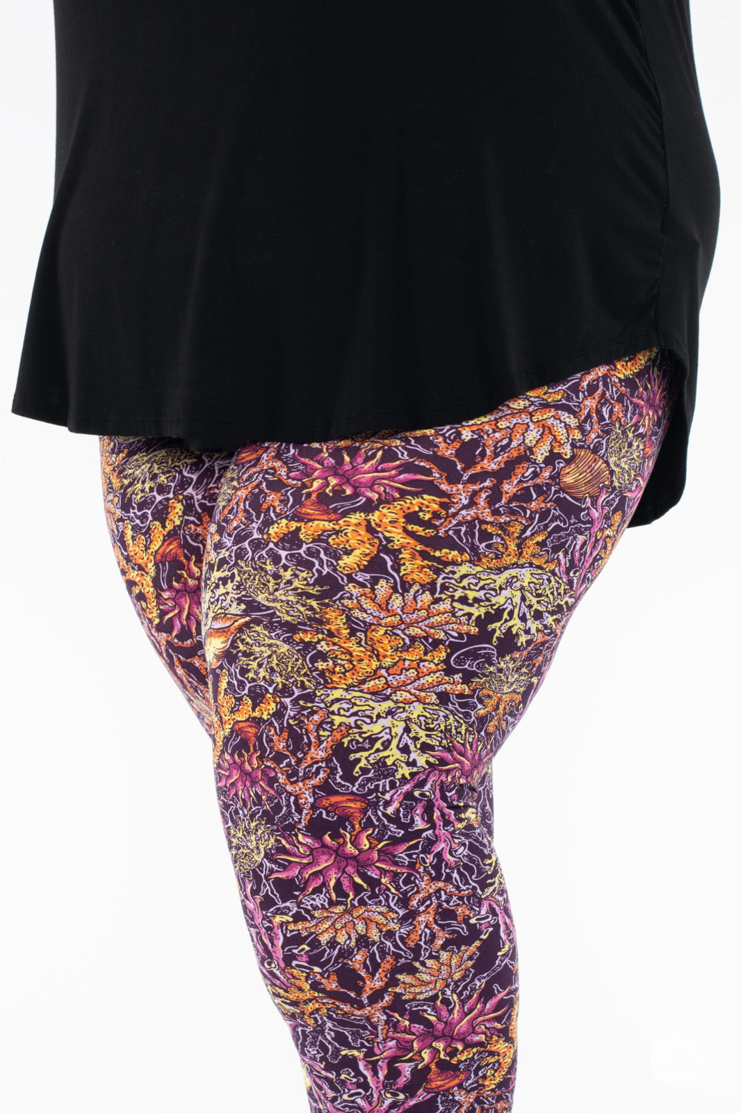 Close-up of SweetLegs Coral Cove Crops with vibrant coral reef pattern in warm tones on a plus size model