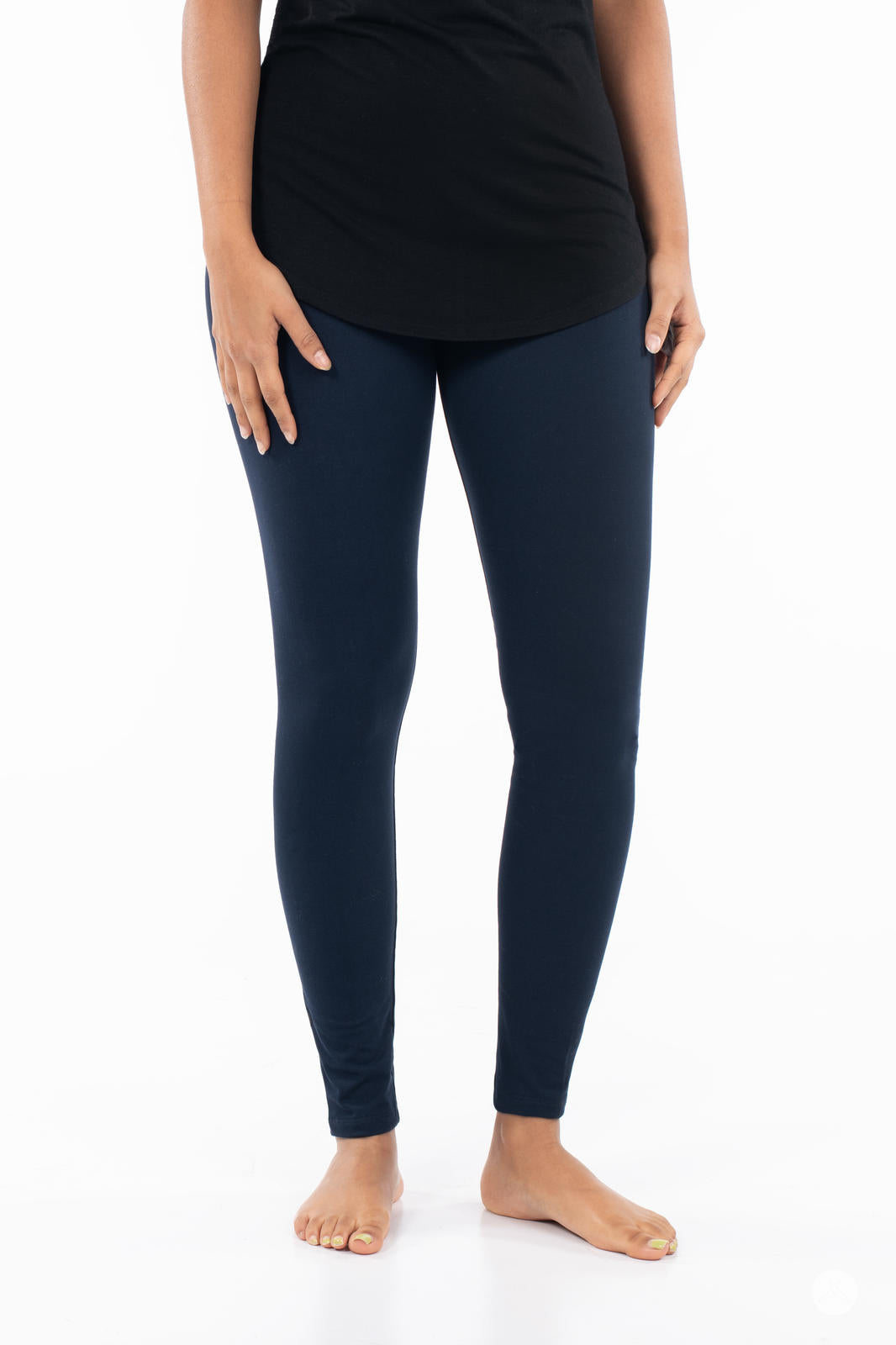 Front view of model wearing Navy leggings by SweetLegs paired with black top barefoot on white background