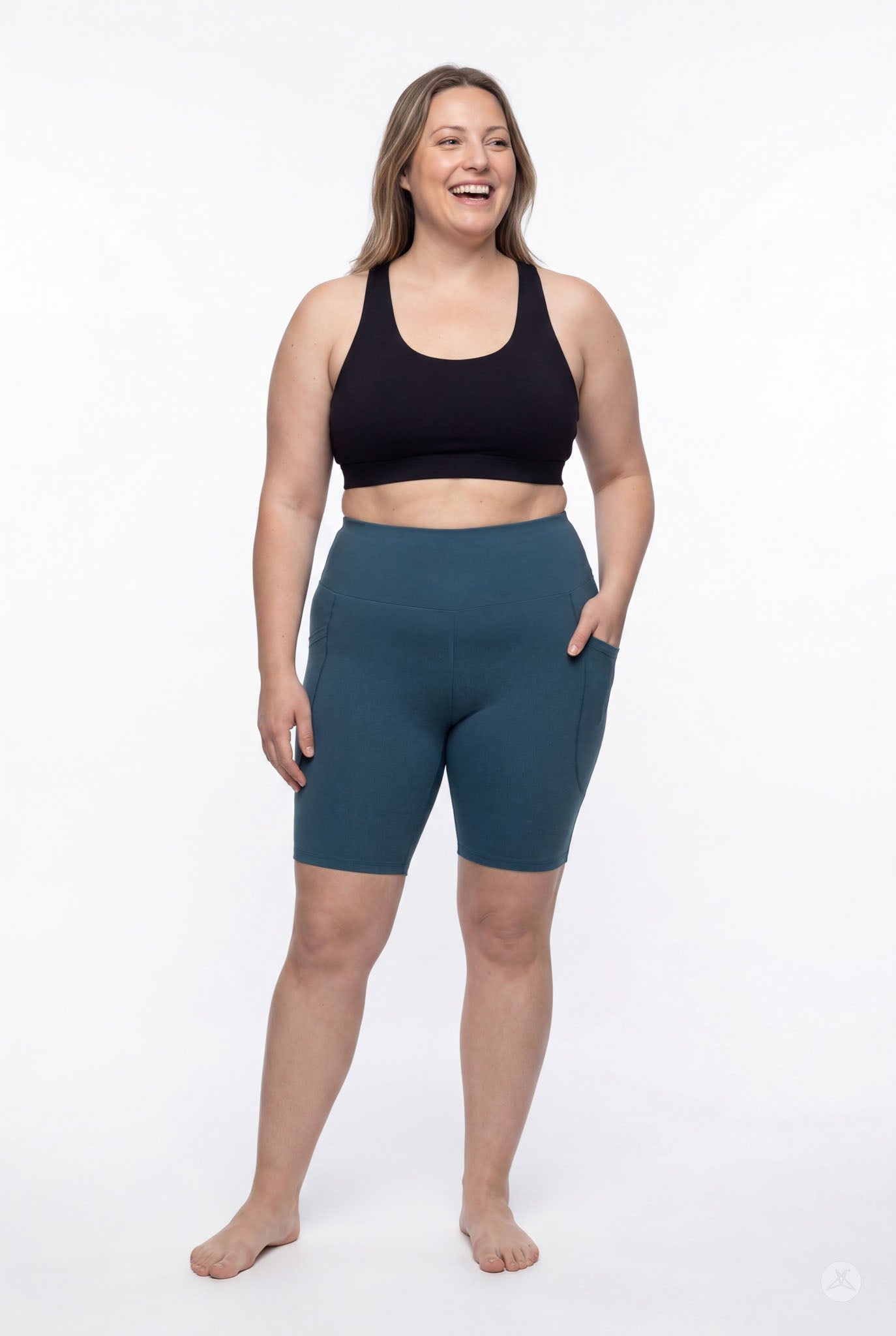 Woman smiling wearing SweetLegs Deep Teal High-Waisted Pocket Biker Shorts with hand in pocket and comfortable fit