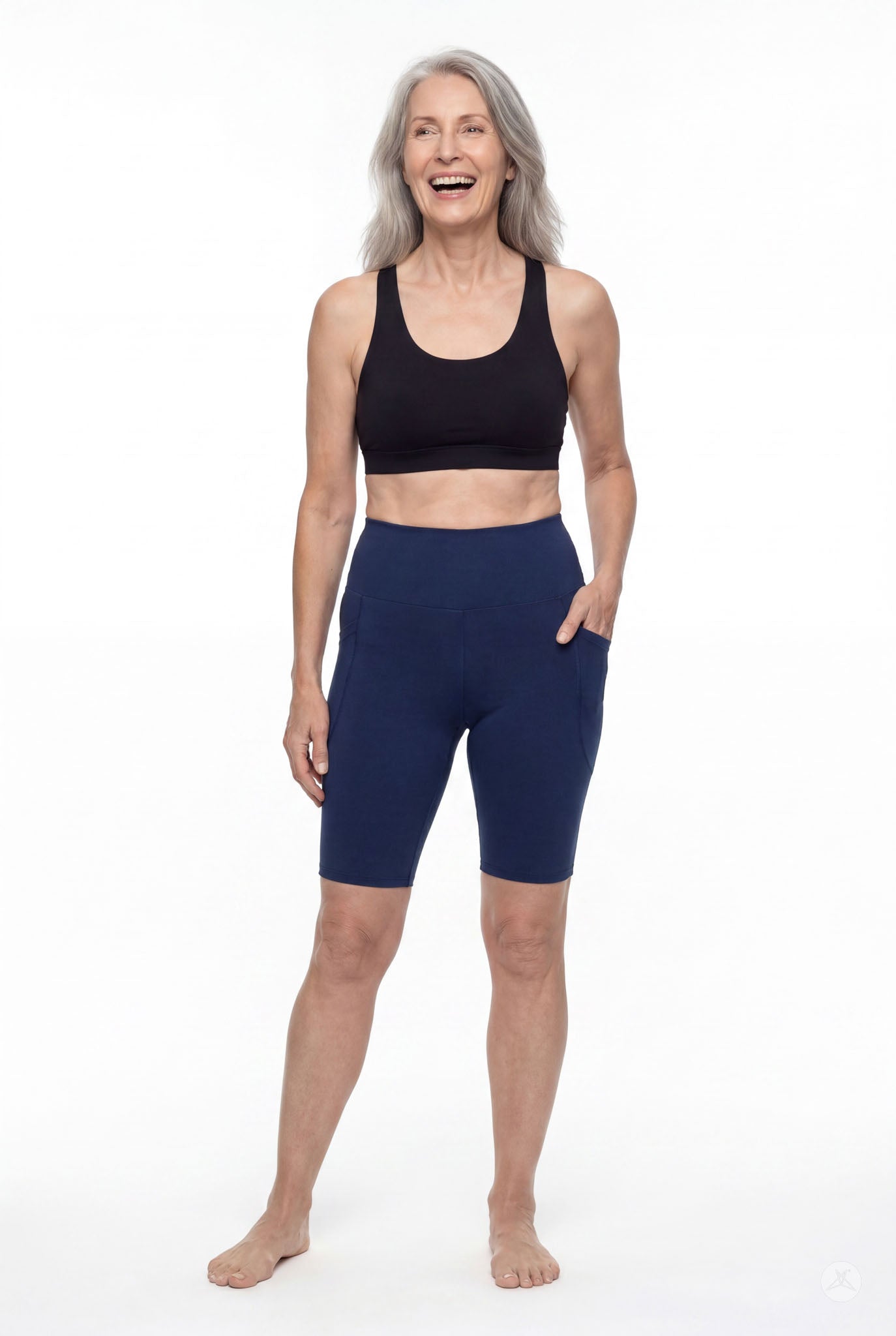 Woman smiling wearing Still Water High-Waisted Pocket Biker Shorts by SweetLegs in navy with side pockets and black sports bra