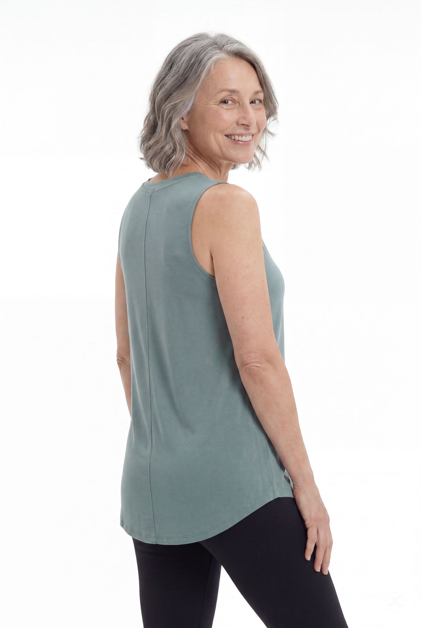 Mature woman smiling wearing SweetTops High Neck Swing Tank in soft muted green with sleeveless relaxed fit from back angle
