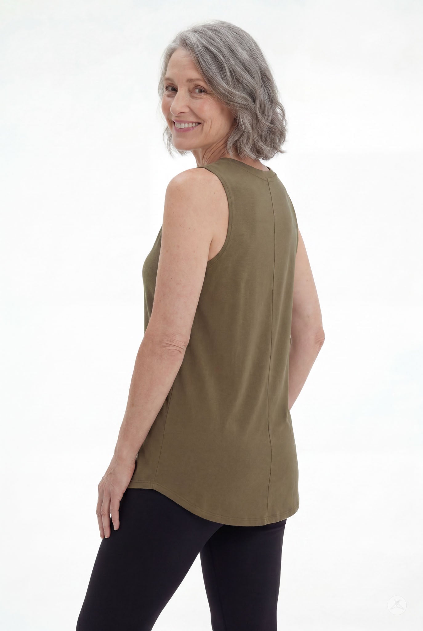Mature woman smiling wearing olive High Neck Swing Tank by SweetTops paired with black leggings on white background
