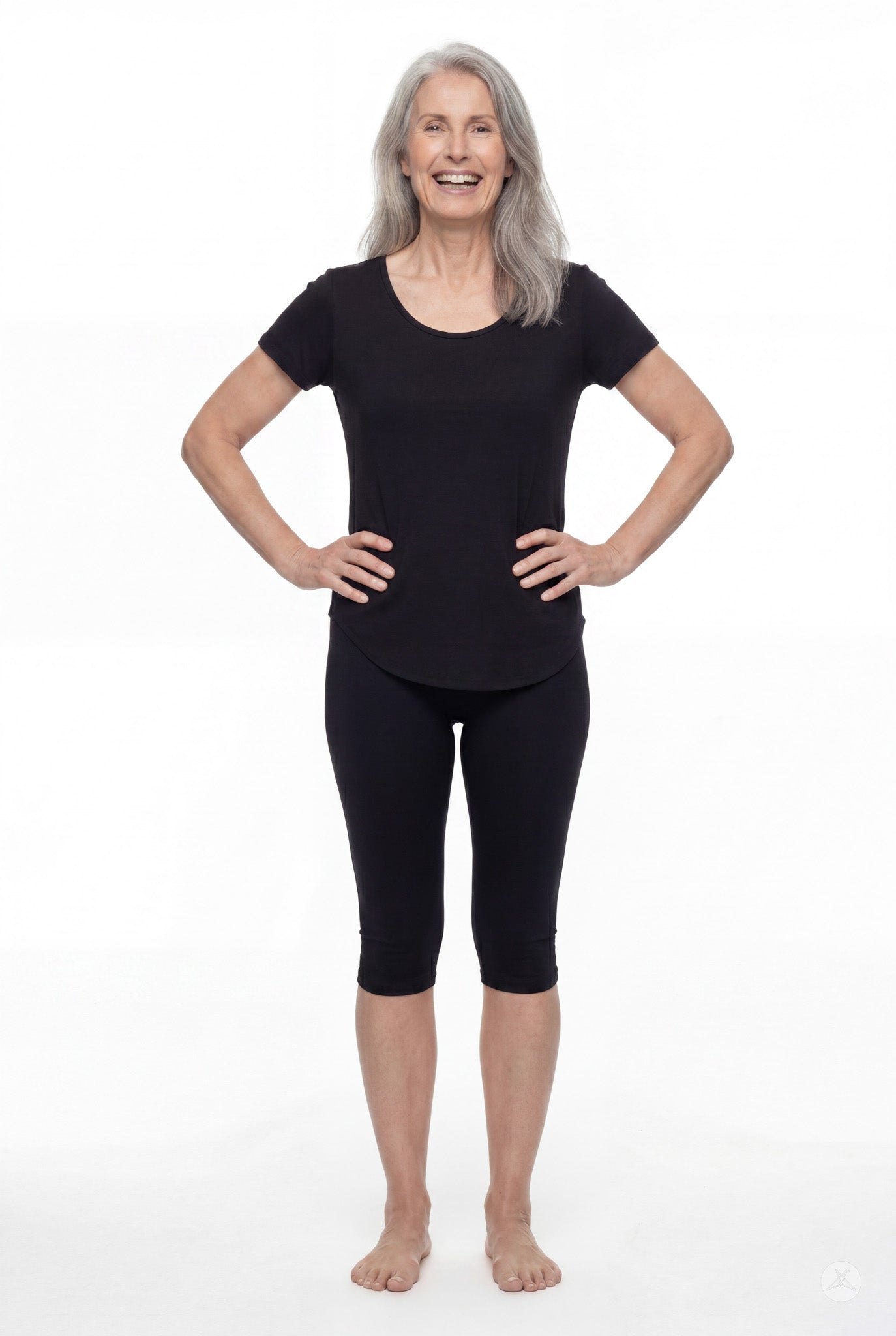 Smiling mature woman wearing black SweetLegs Knee-Length Capri and short-sleeve black top standing barefoot