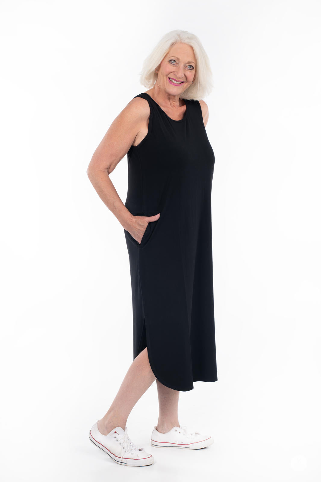 Mature woman smiling wearing SweetTops Sleeveless Tank Dress in black with side slit and pockets on white background