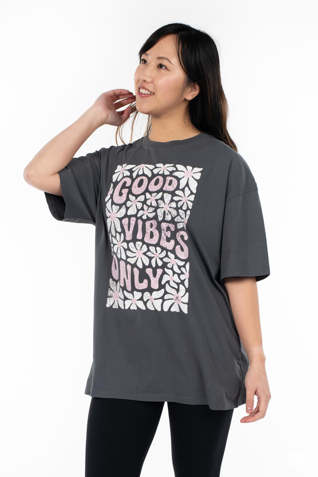 Woman wearing SweetTops Vintage Graphic Tee in charcoal with floral pattern and "Good Vibes Only" positive text design