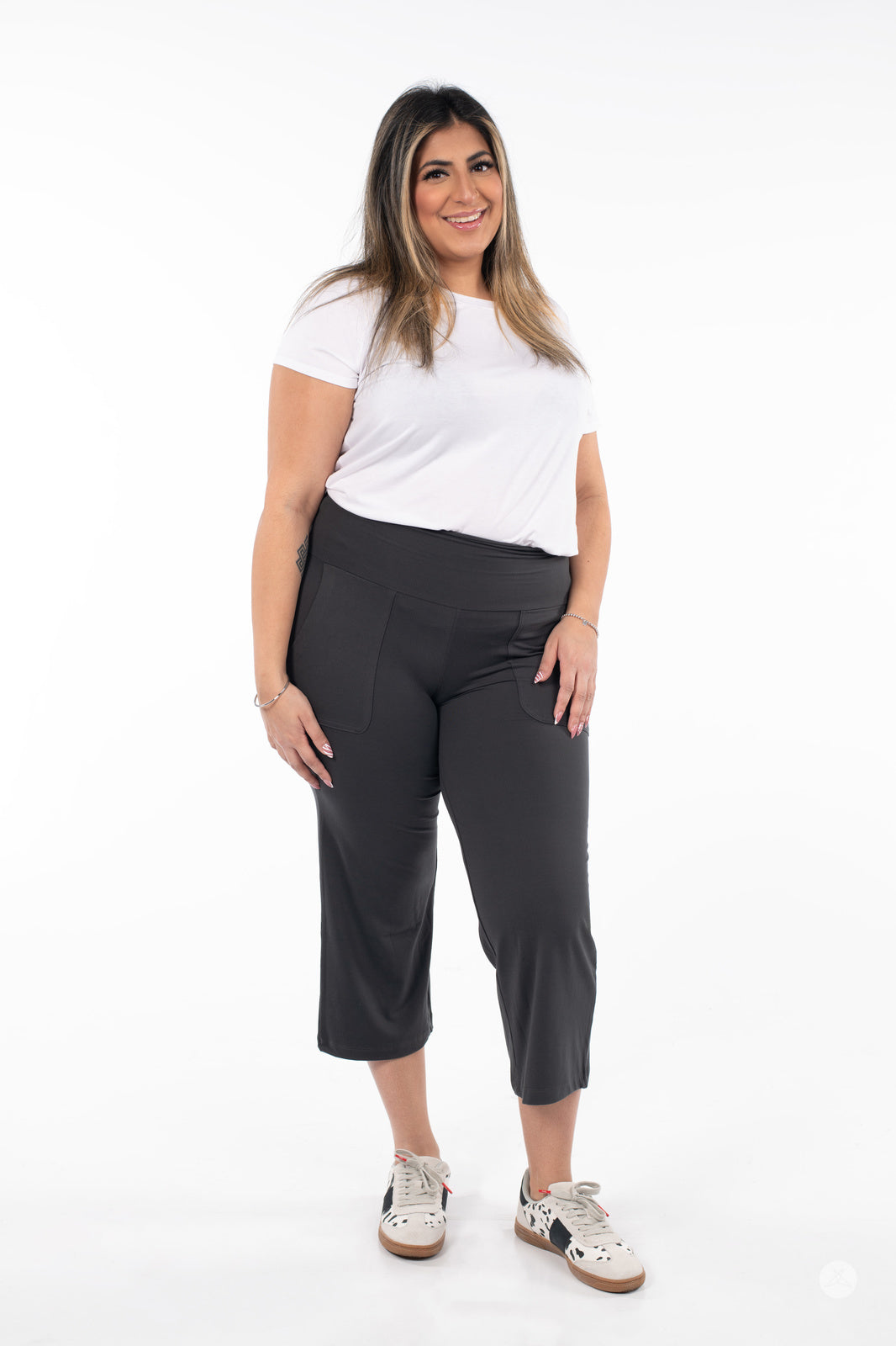 Plus-size model wearing SweetLegs High-Waist Wide Leg Crops in black with patch pockets and white sneakers front view