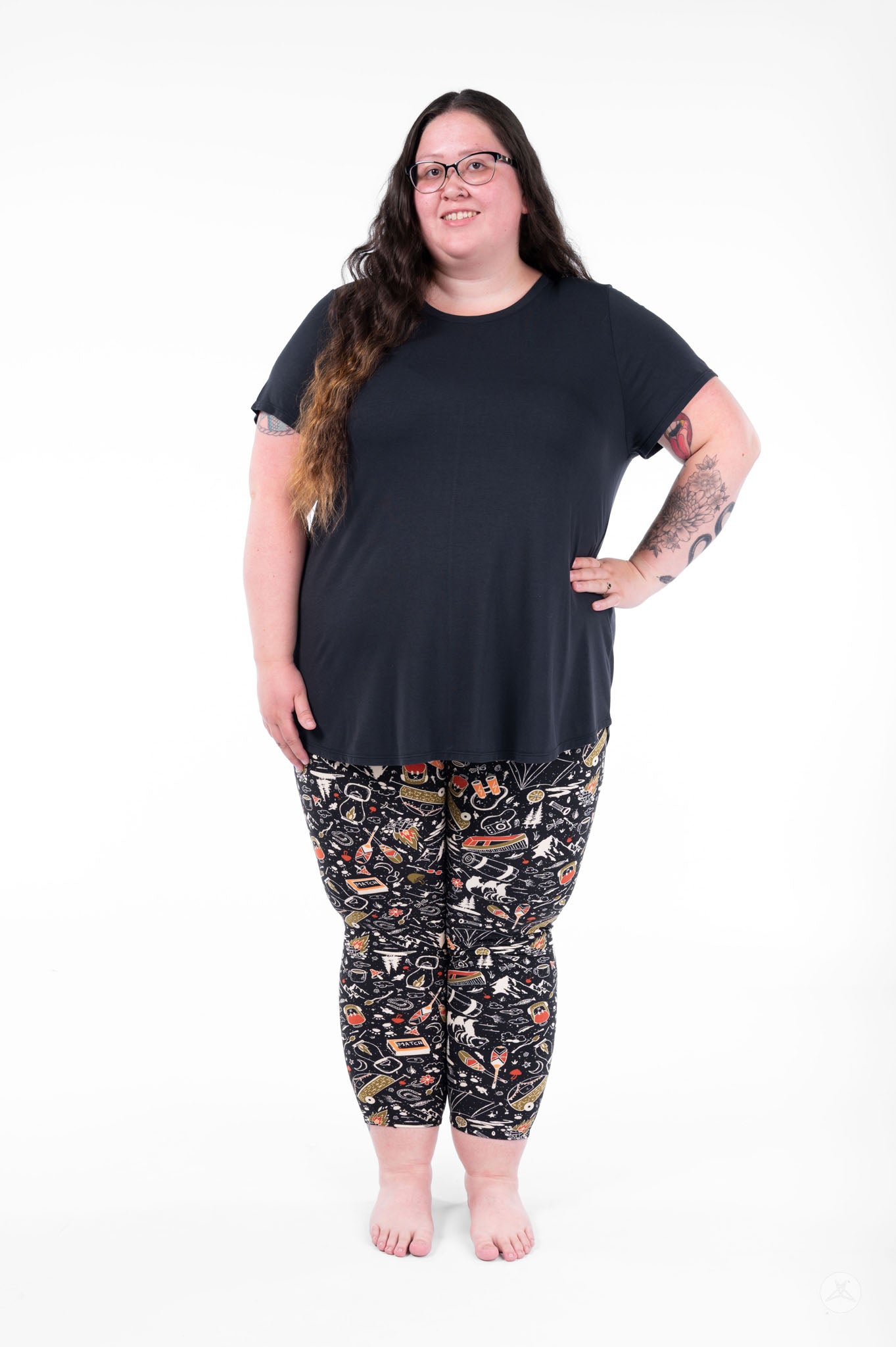 Plus size woman wearing SweetLegs Off Grid Crops with black outdoor pattern and black top standing barefoot facing forward