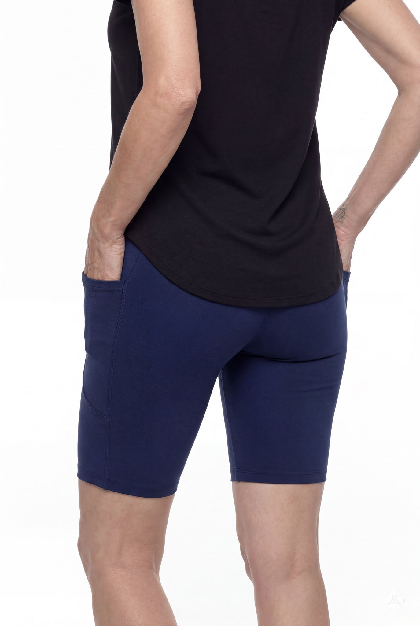 Woman wearing SweetLegs Still Water Pocket Biker Shorts in navy with side pockets and smooth waistband from the back view