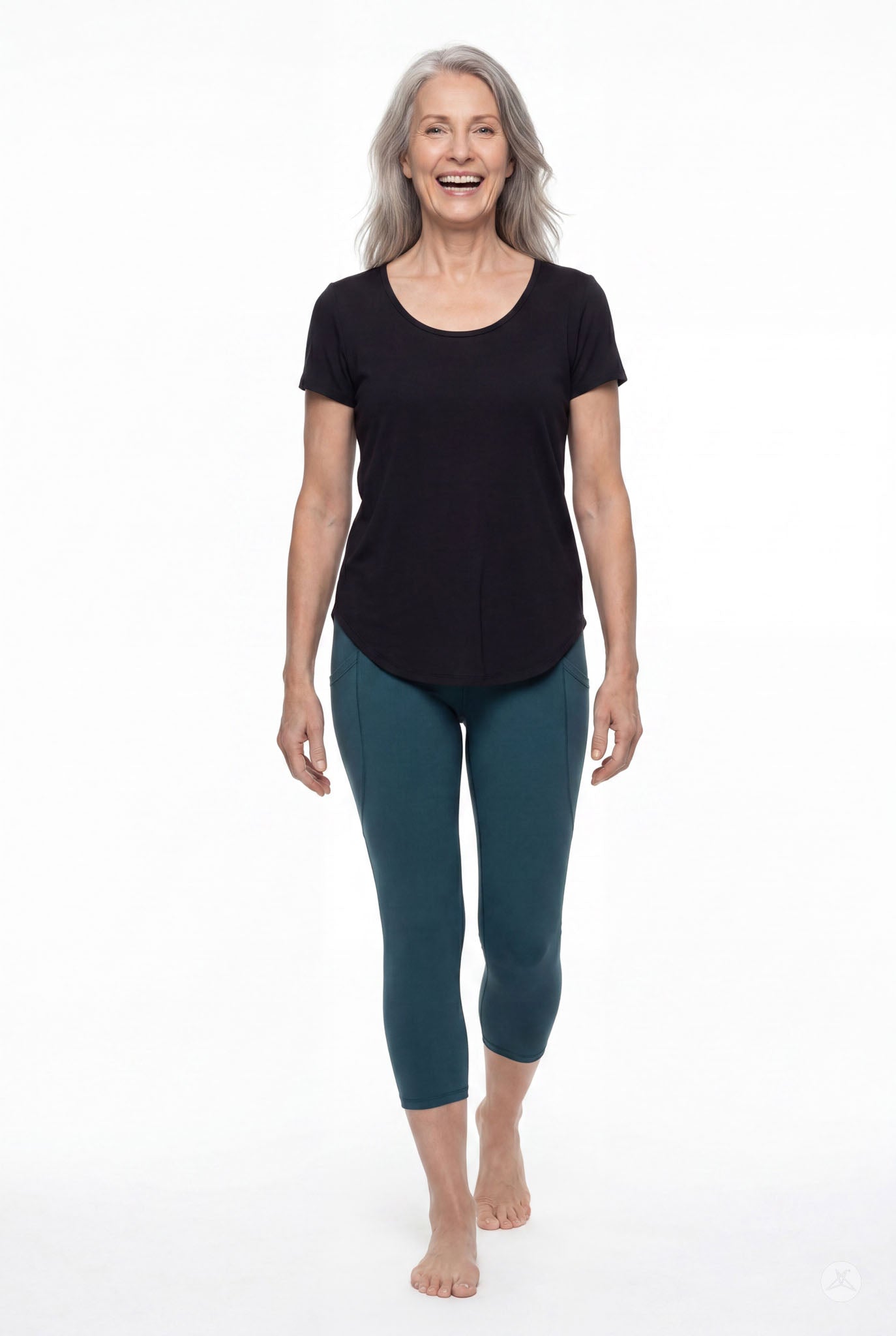 Plus size woman smiling wearing SweetLegs Deep Teal Pocket Crops leggings and black top walking barefoot front view