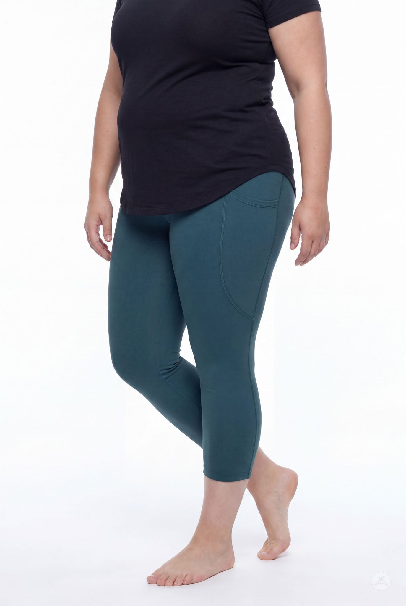 Plus size woman wearing SweetLegs Deep Teal Pocket Crops with side pockets and black top standing barefoot side view