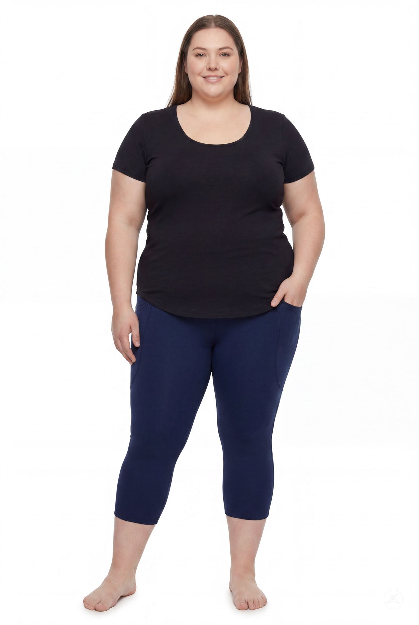Plus size woman standing barefoot wearing SweetLegs Still Water Pocket Crops navy leggings with black top front view