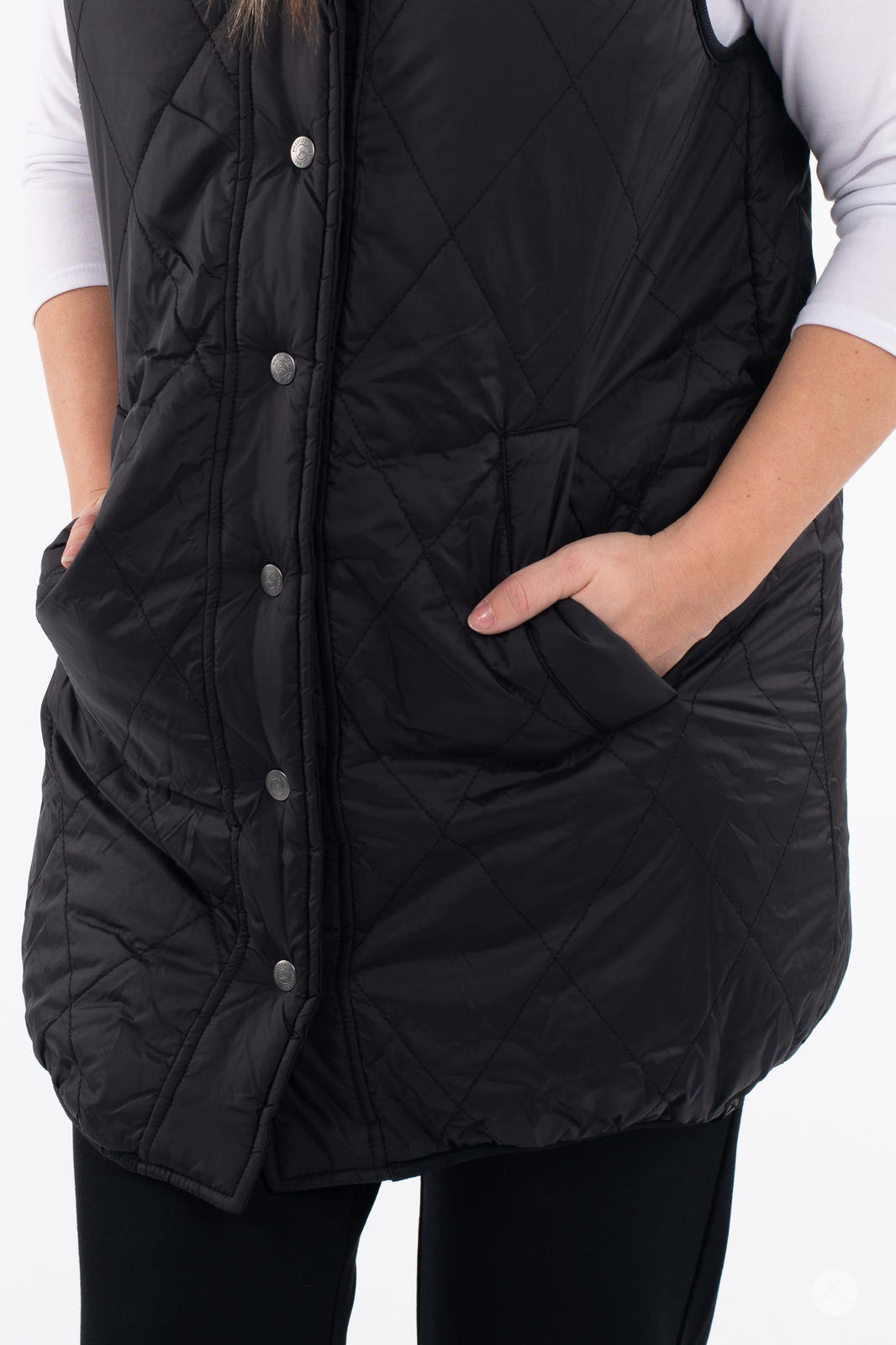 Woman wearing black Reversible Quilted Sherpa Vest by SweetLegs Canada with hands in front pockets and snap buttons visible
