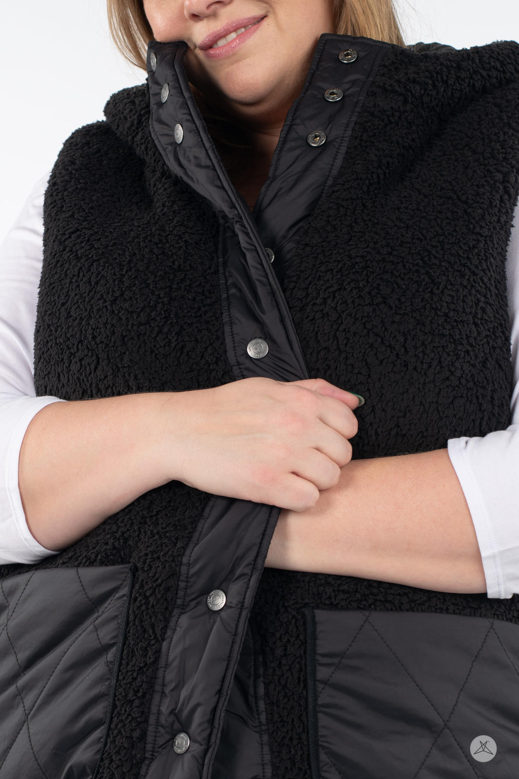 Close-up of woman fastening front snaps on black SweetLegs Canada Reversible Quilted Sherpa Vest