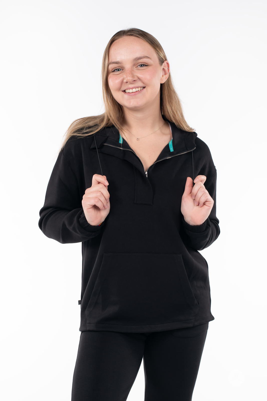 Smiling woman wearing black SweetTops All Day Hoodie with front pocket and half zip on white background