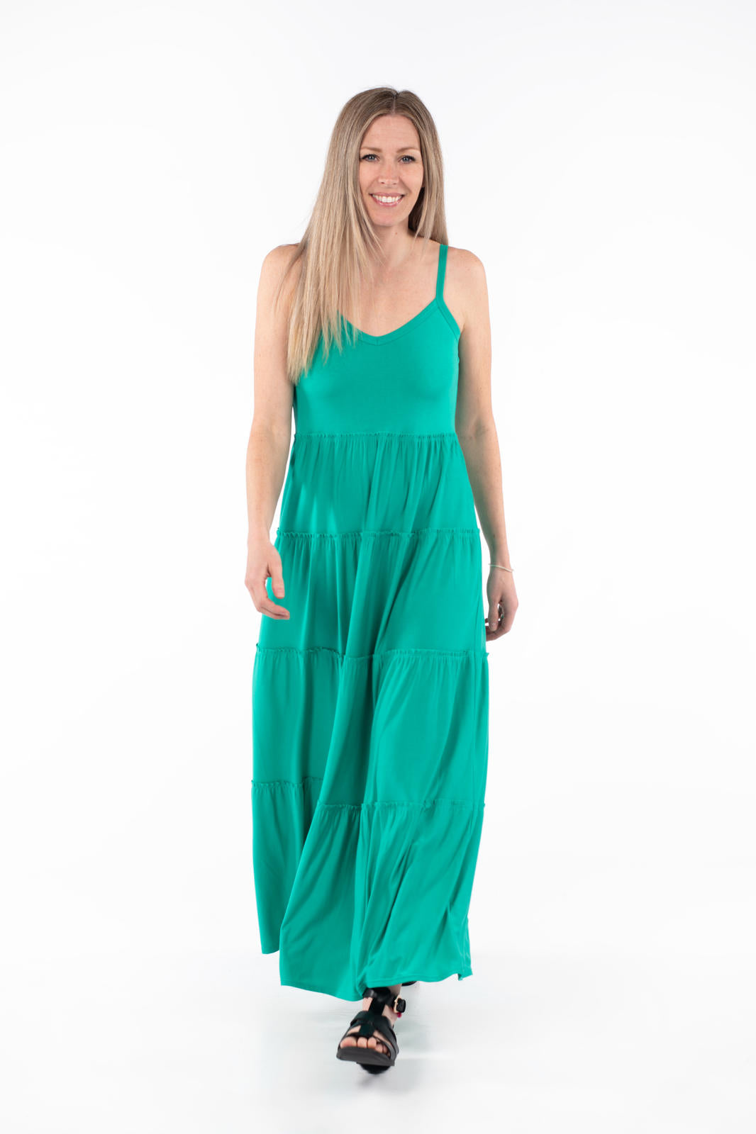 Woman walking in vibrant green The Summer Tiered Dress by SweetTops with adjustable straps and flowing maxi skirt