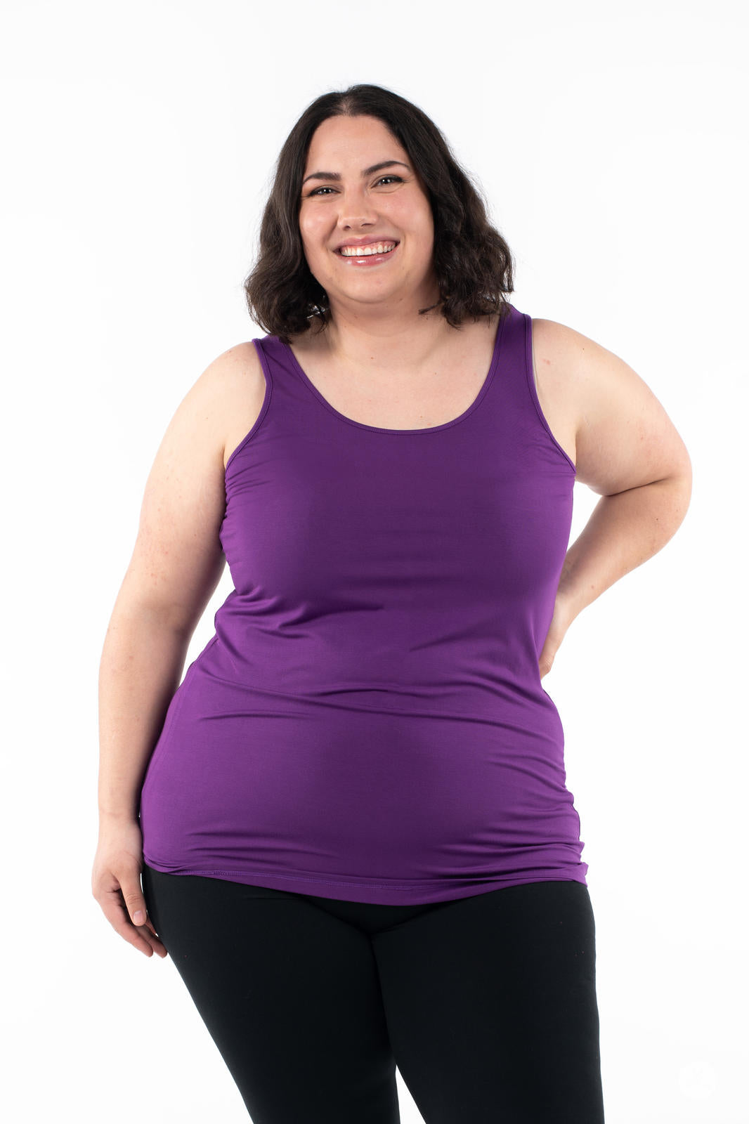 Smiling plus size woman wearing deep purple Classic Layering Tank by SweetLegs Canada with black leggings on white background