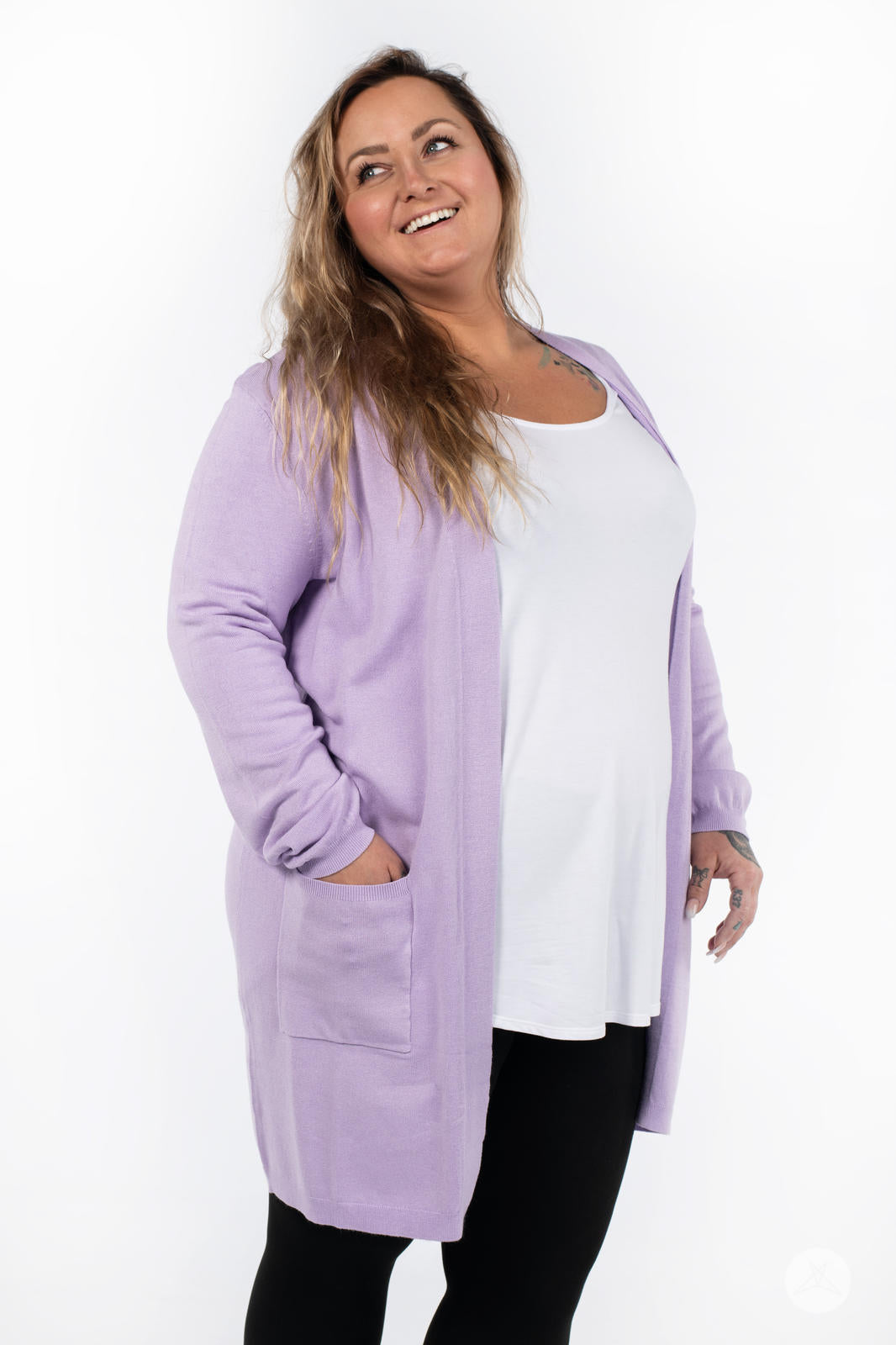 Plus-size model smiling wearing SweetLegs Canada Spring Cardigan in soft lavender with front patch pockets and black leggings