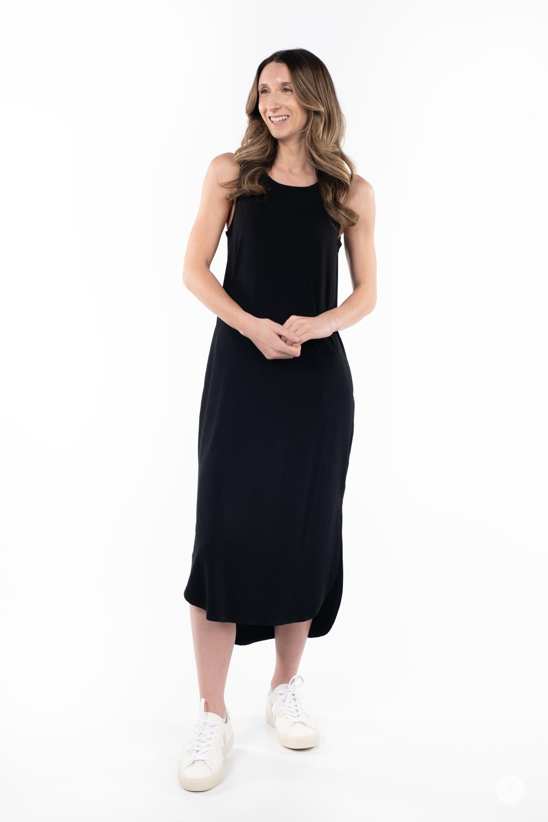 Smiling woman wearing SweetTops Sleeveless Tank Dress in black with a relaxed fit and sneakers on white background