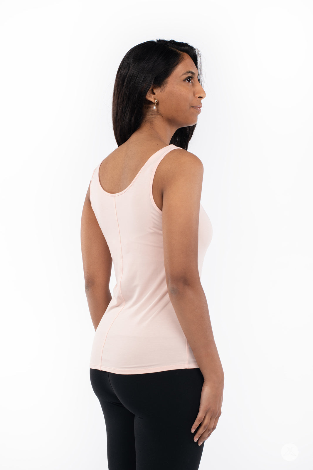 Woman wearing SweetLegs Canada Classic Tank in latte, shown from side back with black leggings on white background