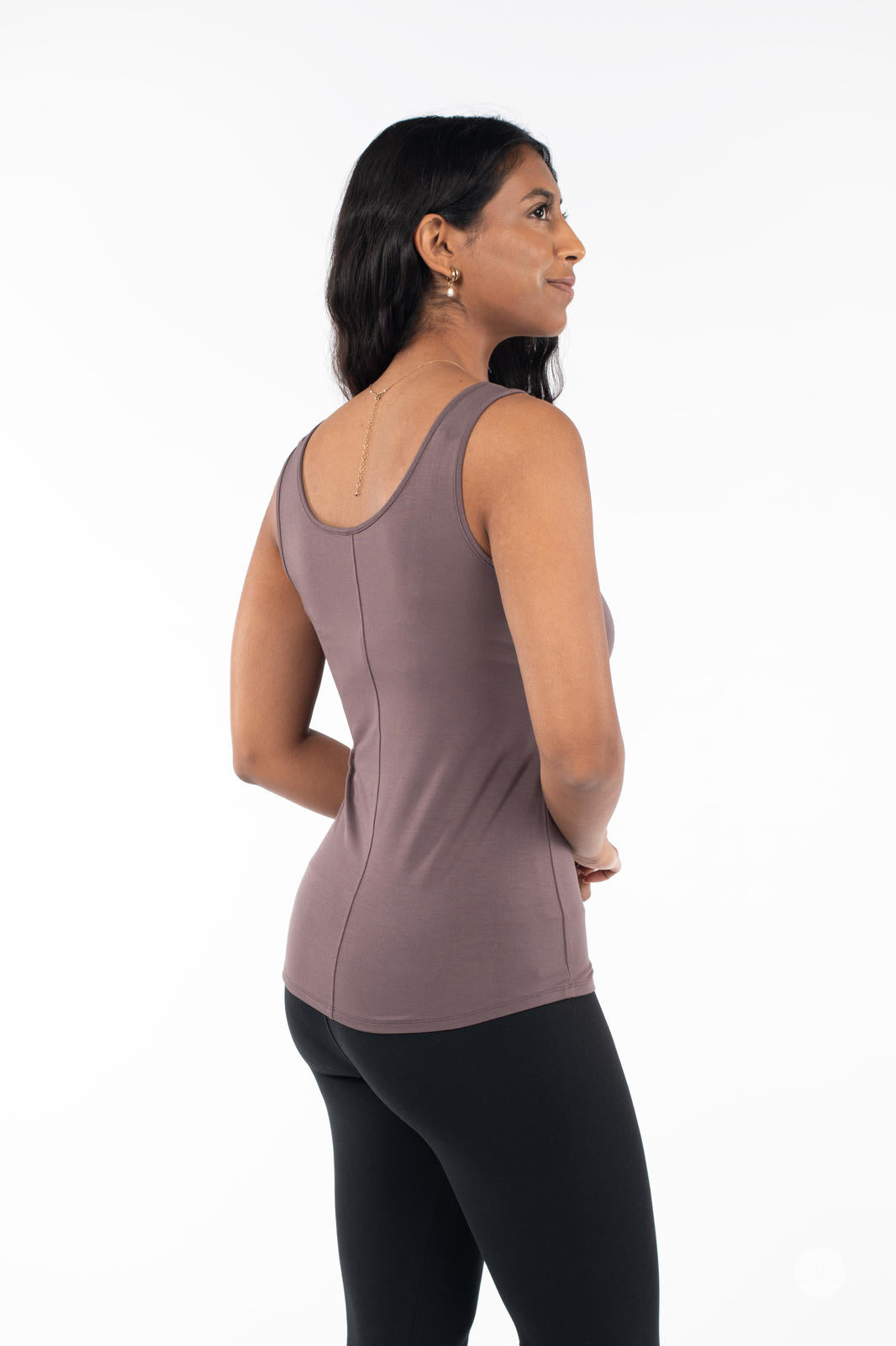 Woman facing sideways wearing SweetLegs Canada Classic Tank in Latte paired with black leggings on white background