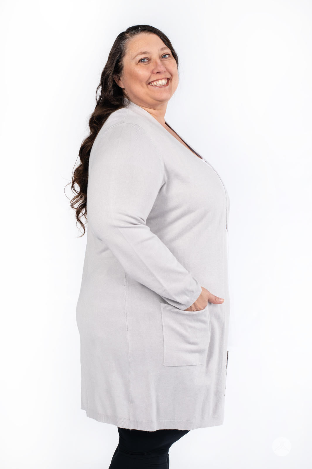 Smiling model wearing SweetLegs Canada Spring Cardigan in light grey with patch pockets in side profile view