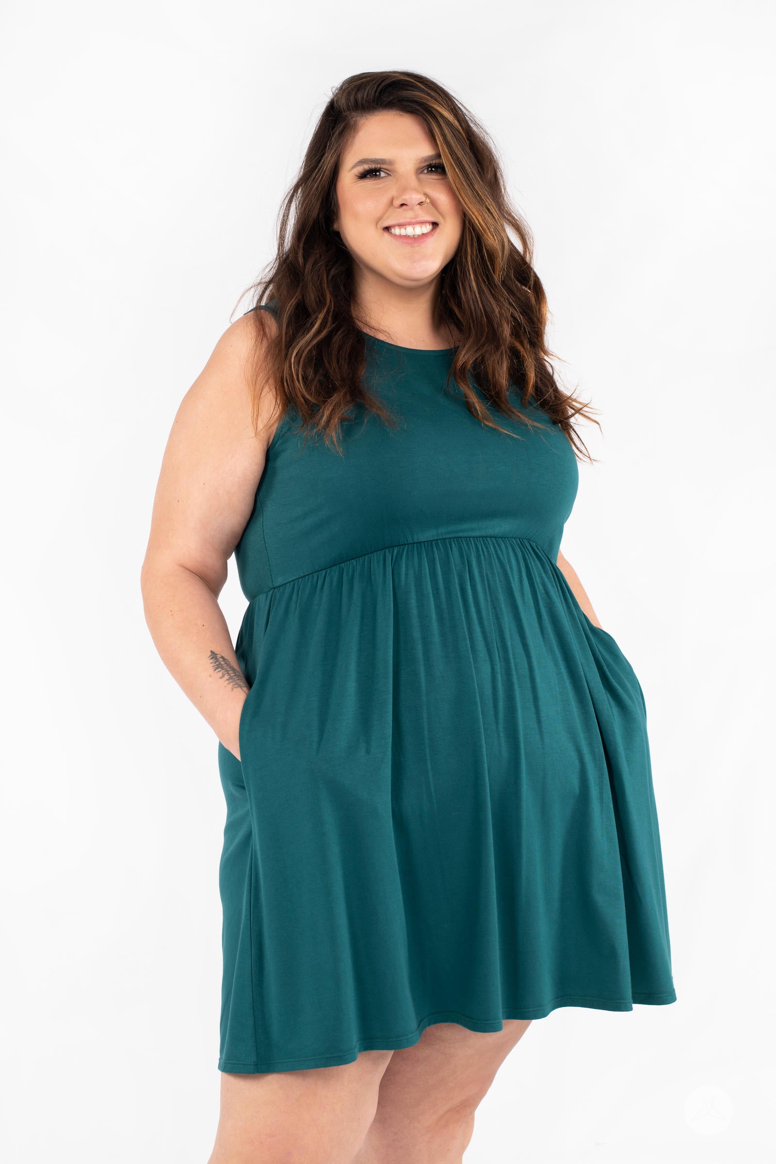 Plus-size model smiling wearing SweetTops The Weekender Dress in teal with pockets on white background