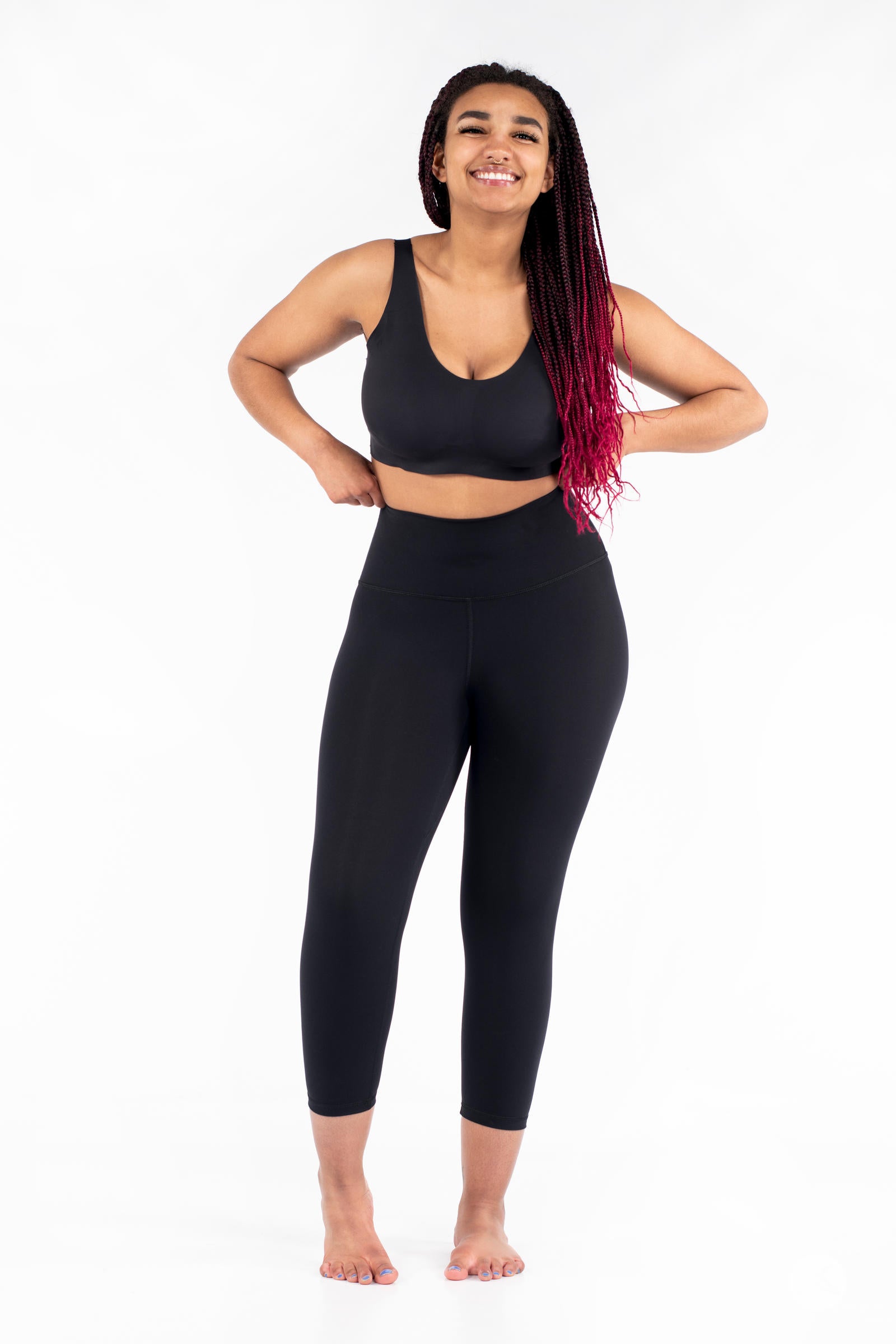 Smiling woman wearing black Free Motion Crops by Athleisure SweetLegs standing barefoot with hands on hips front view