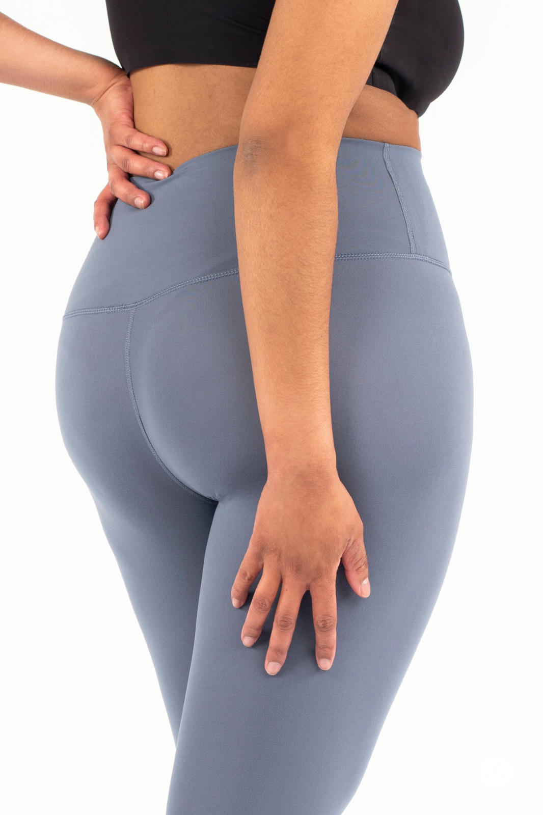 Rear view of model wearing blue Free Motion Crops by Athleisure SweetLegs collection with hand resting on hip