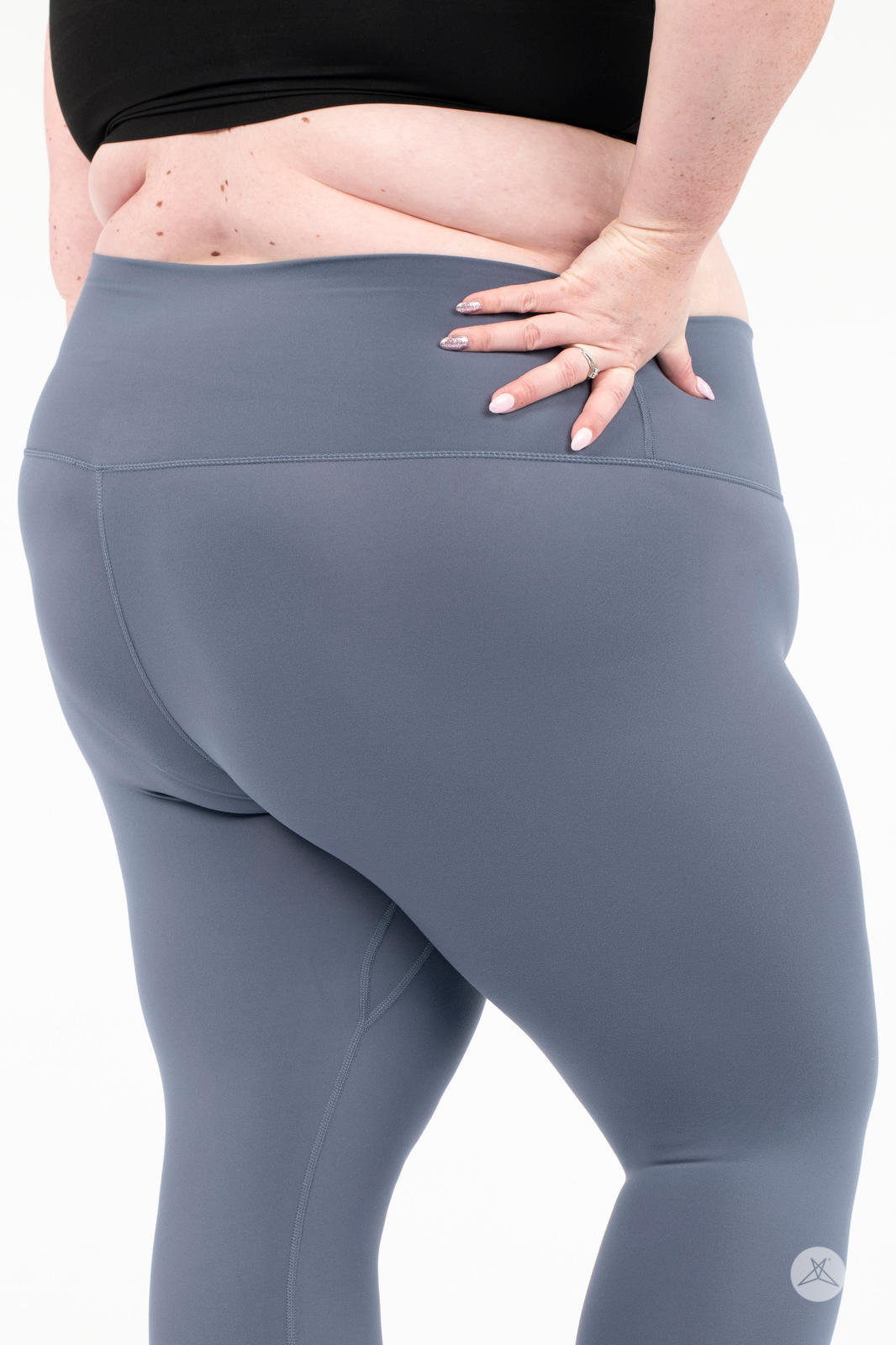 Rear view of plus-size woman wearing gray Free Motion Crops by Athleisure SweetLegs with hand on hip on white background
